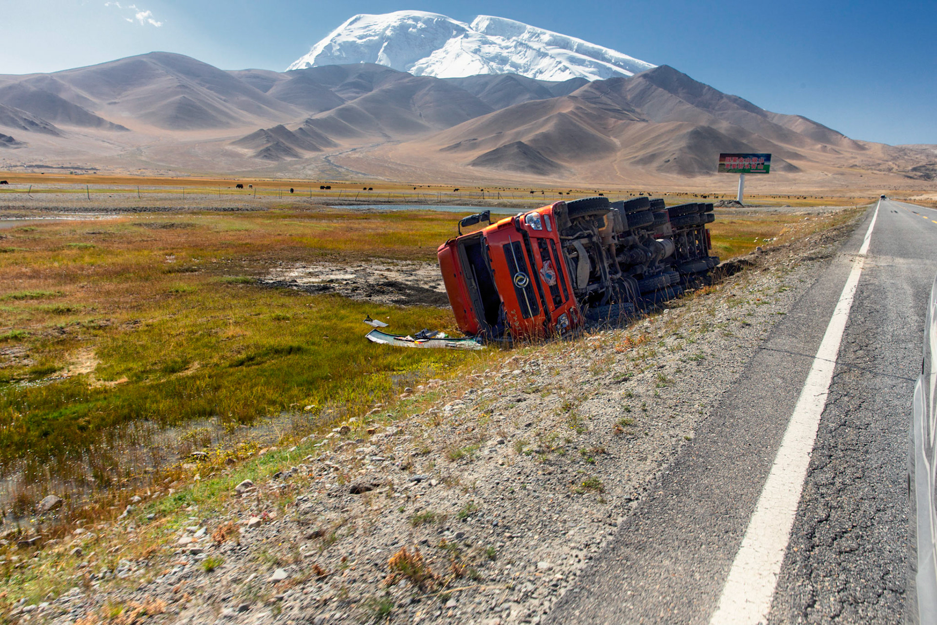 Red truck, toppled over to the side of the Karakoram highway. Red trucks are the iconic transport vehicles all over China.