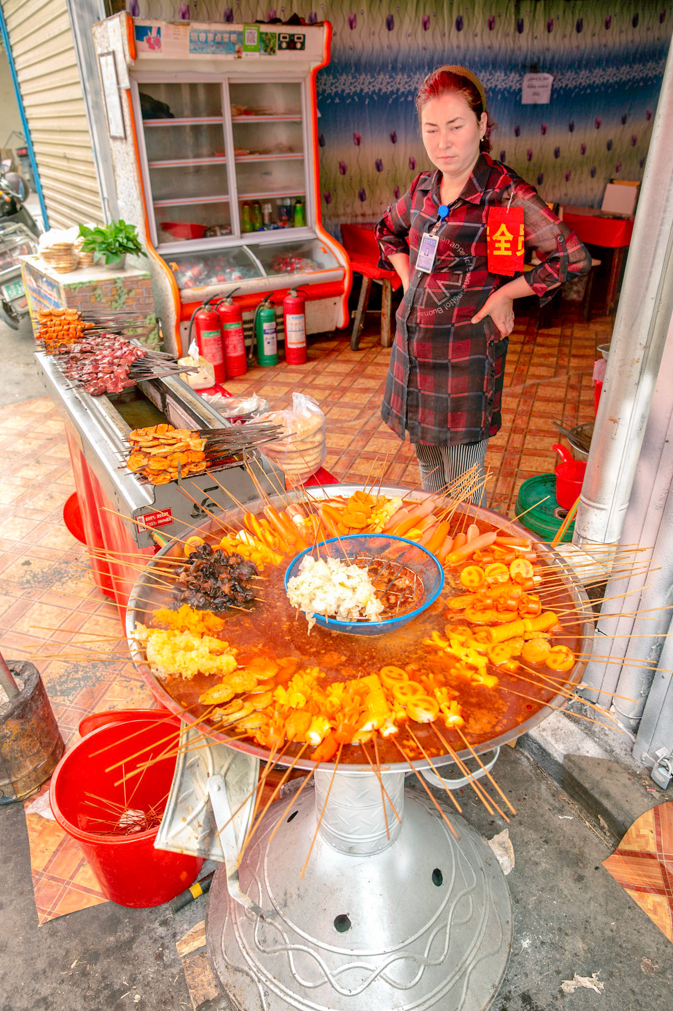 Kashgar, Xinjiang, China - September 5, 2018: Woman looking at the prepared food , ready for lunch, at a food stall in the Kashgar Grand Bazaar