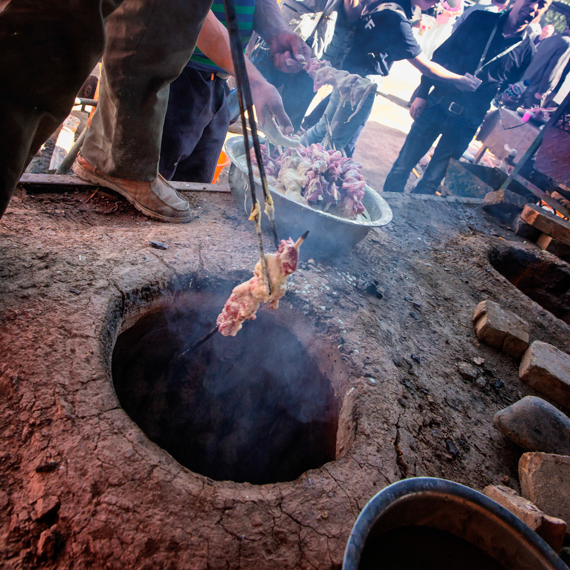Kashgar,  China - September 9th, 2018 : Man preparing the fire to grill battered lamb meat at the Kasghar cattle market.