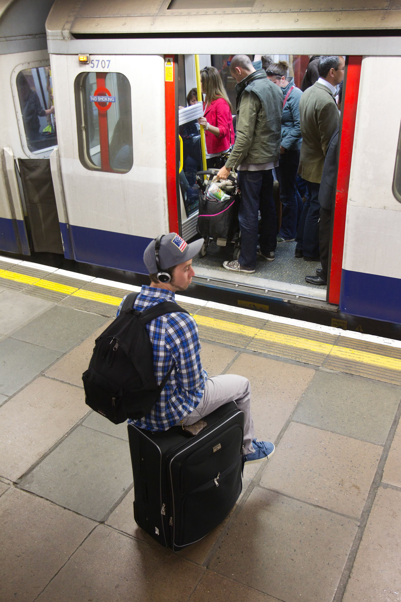 London May 3, 2011 - Joel Johnson, a student in london, sitting on top of his suitcase looking at an open door of a london underground carriage. Joel decided to wait for the next train.