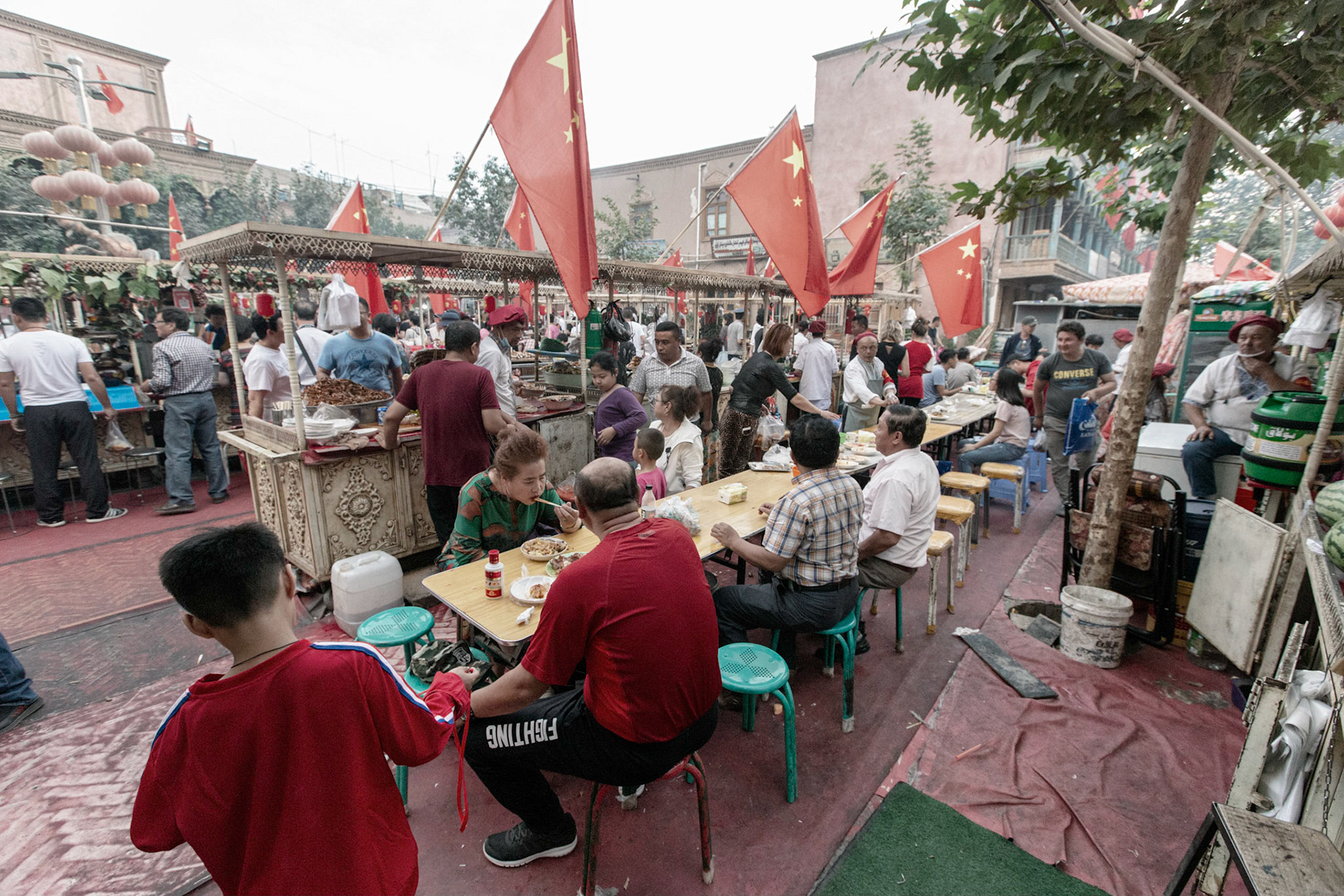 Kashgar,  China - September 11th, 2018 : People enjoying food at the Kashgar food market, many food stalls and many chinese flags