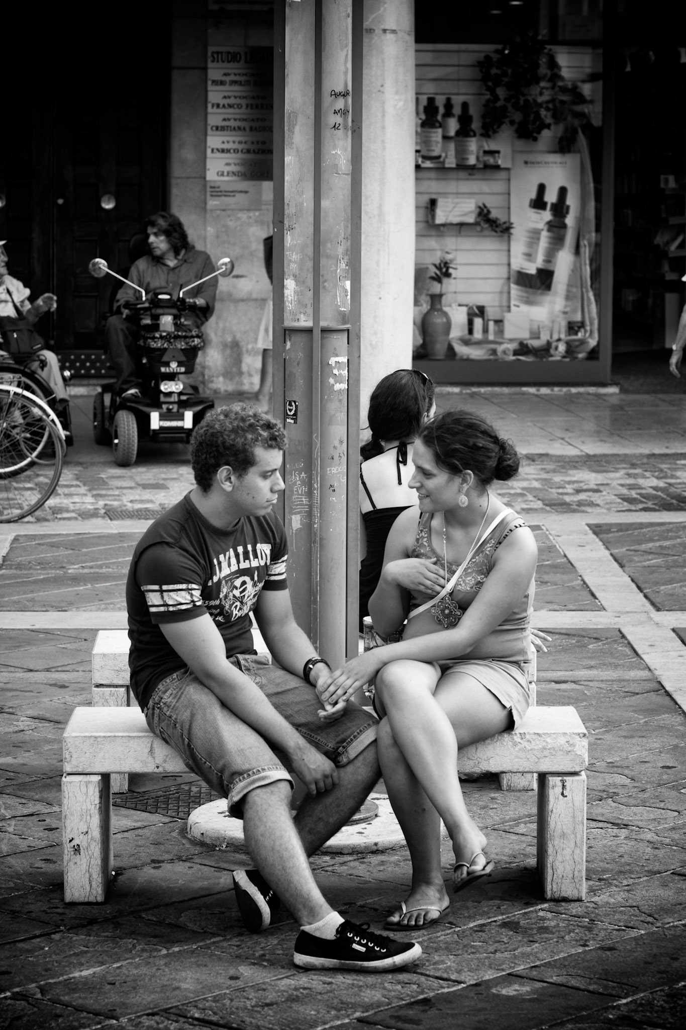 Rimini, Italy - july 30th, 2012 : young couple sitting on a bench in Rimini, some people and shopfronts in the background  [url=http://www.istockphoto.com/search/lightbox/11293042#64eec1d][img]http://www.piebinga.nl/banners/italy.jpg[/img][/url]