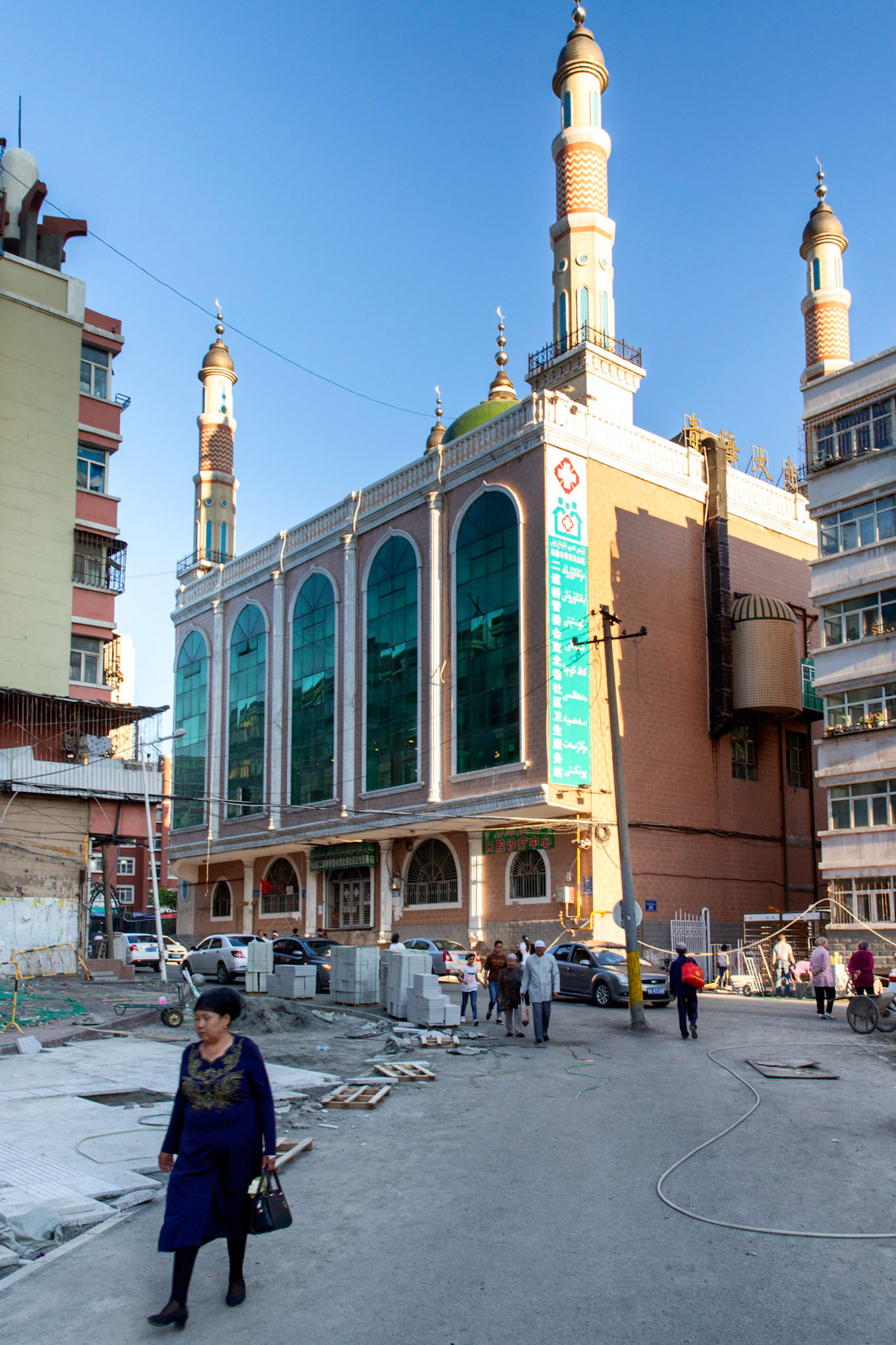 Urumqi, China - september 1, 2018 : people walking in front a modern mosque in Urumqi. The mosque has traditional islam ornamets and towers, as well as a chinese characters and a modern architecture for the main building.
