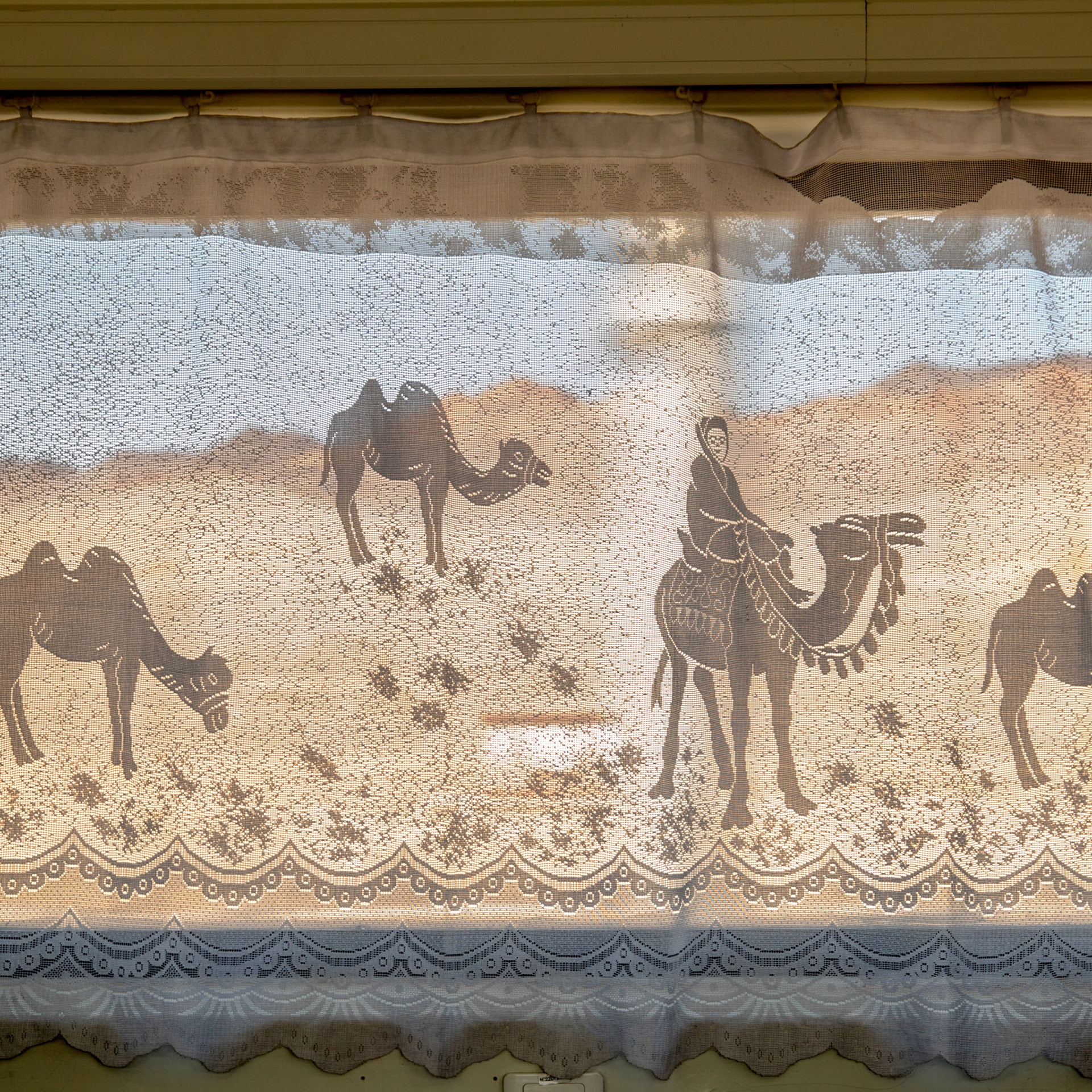 Curtain decorated with a camel caravan scene  in a train in Xinjiang, China, desert can be seen in the background.