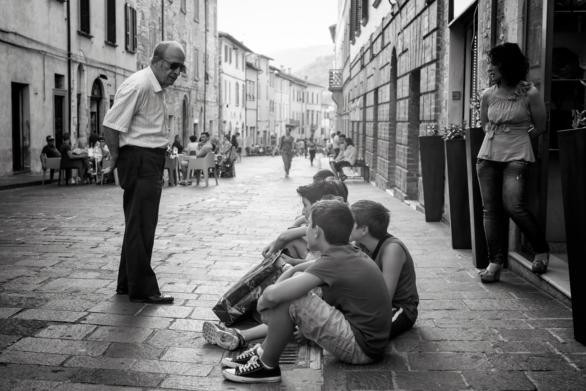 Gubbio, Italy - man talking to a broup of boys sitting on the sidwalk on one of the streets in Gubbio. This street closes at 6pm for all cars so that pedestrians can relax, sit in outdoor restaurants and generally enjoy the cool evenings url=http://www.istockphoto.com/search/lightbox/11293042#64eec1d][img]http://www.piebinga.nl/banners/italy.jpg[/img][/url]