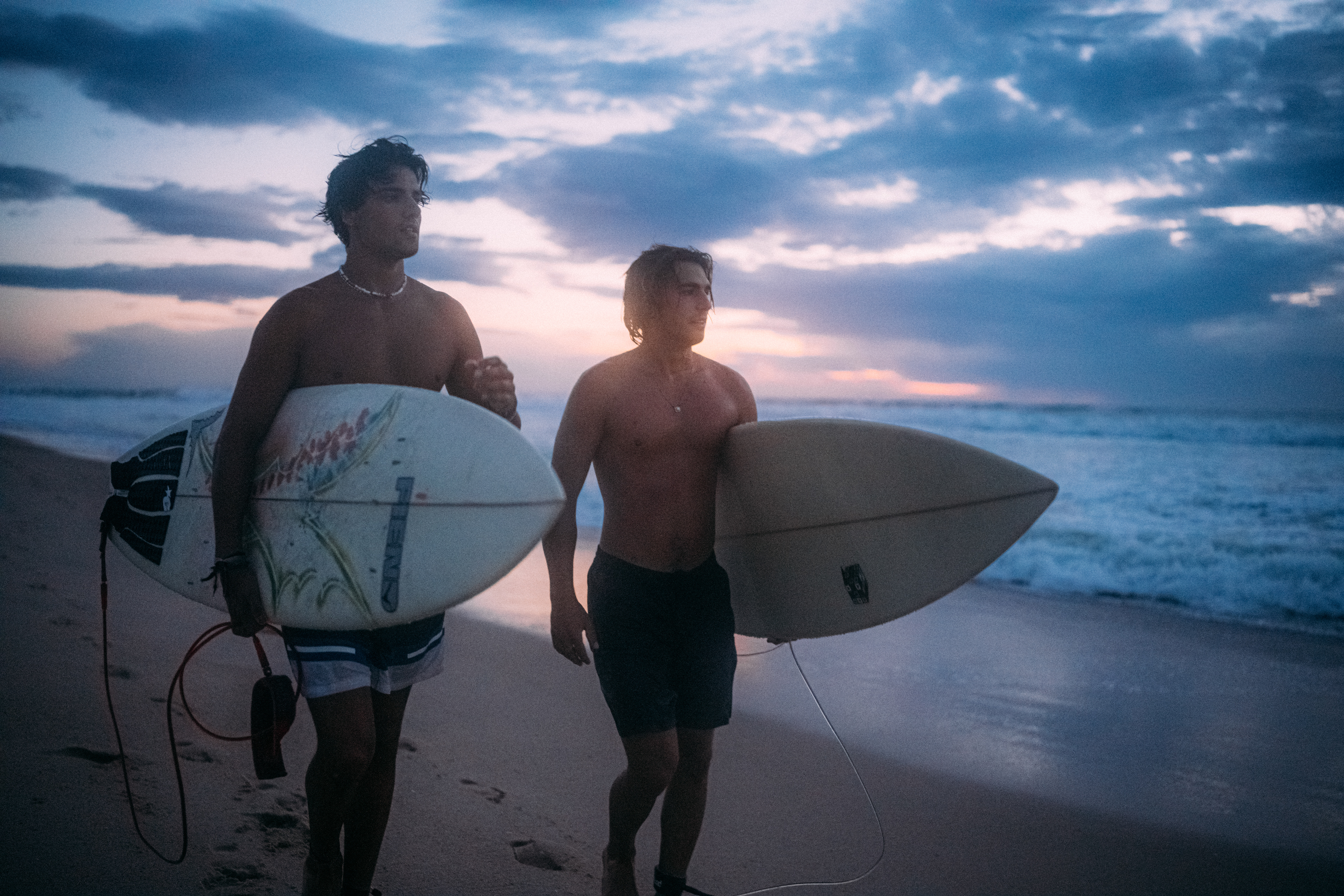 Spiegelung des Himmels auf der Wasseroberfläche, während ein Surfer auf die nächste Welle wartet.