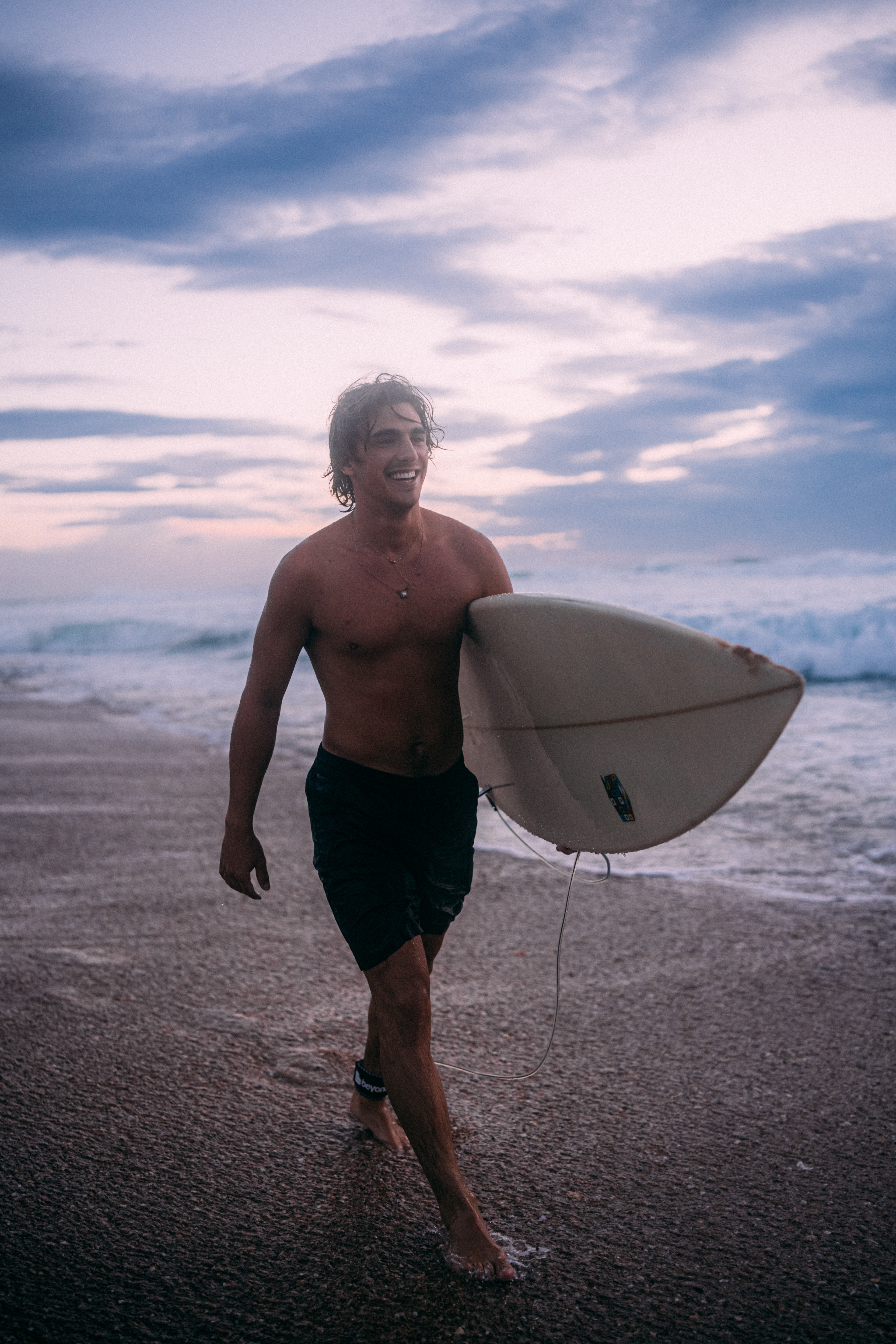 Surfer fängt eine letzte Welle, während der Himmel in den Farben der Dämmerung leuchtet.