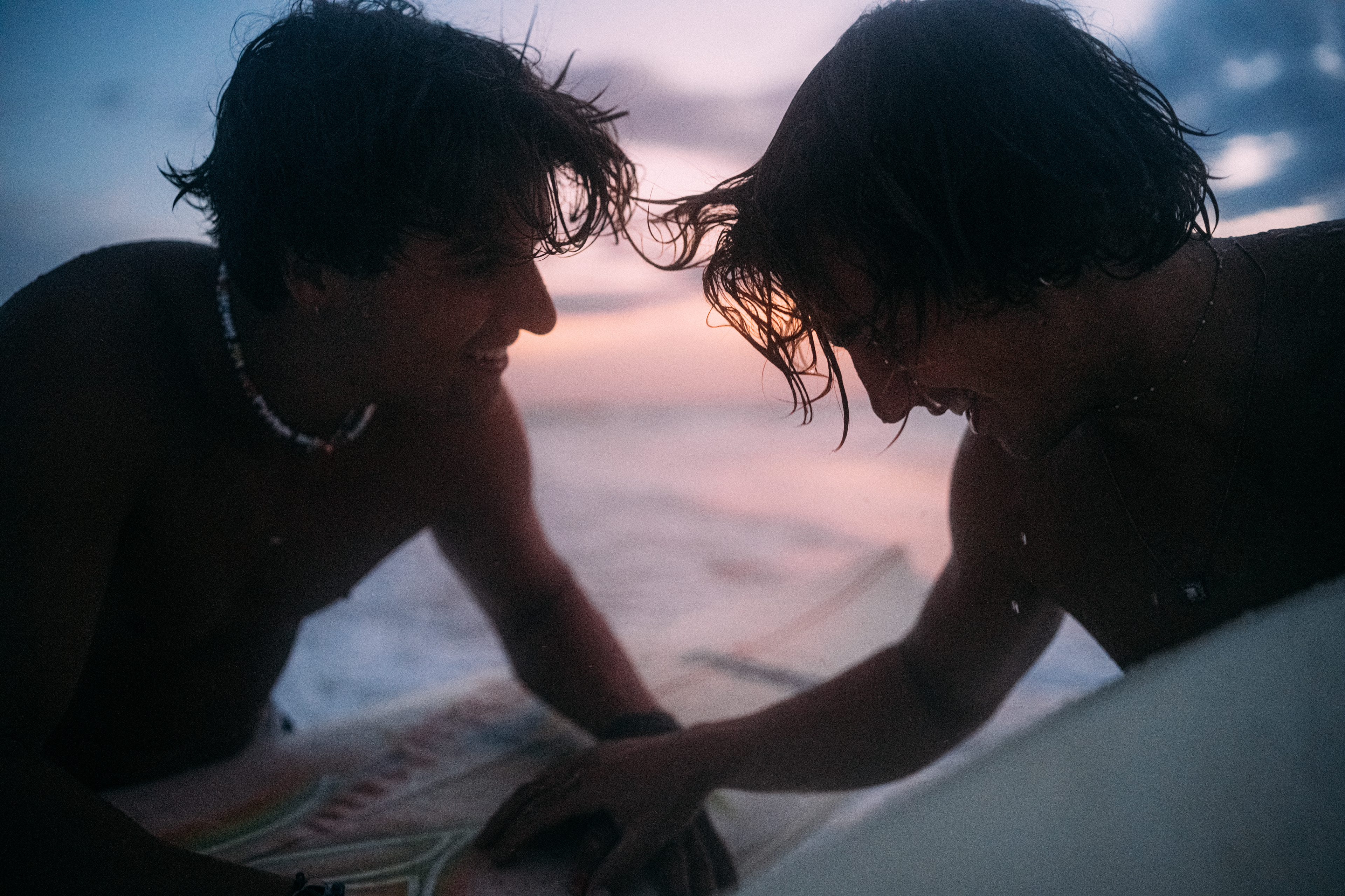 Silhouette eines Surfers vor dem farbenprächtigen Himmel der Blauen Stunde