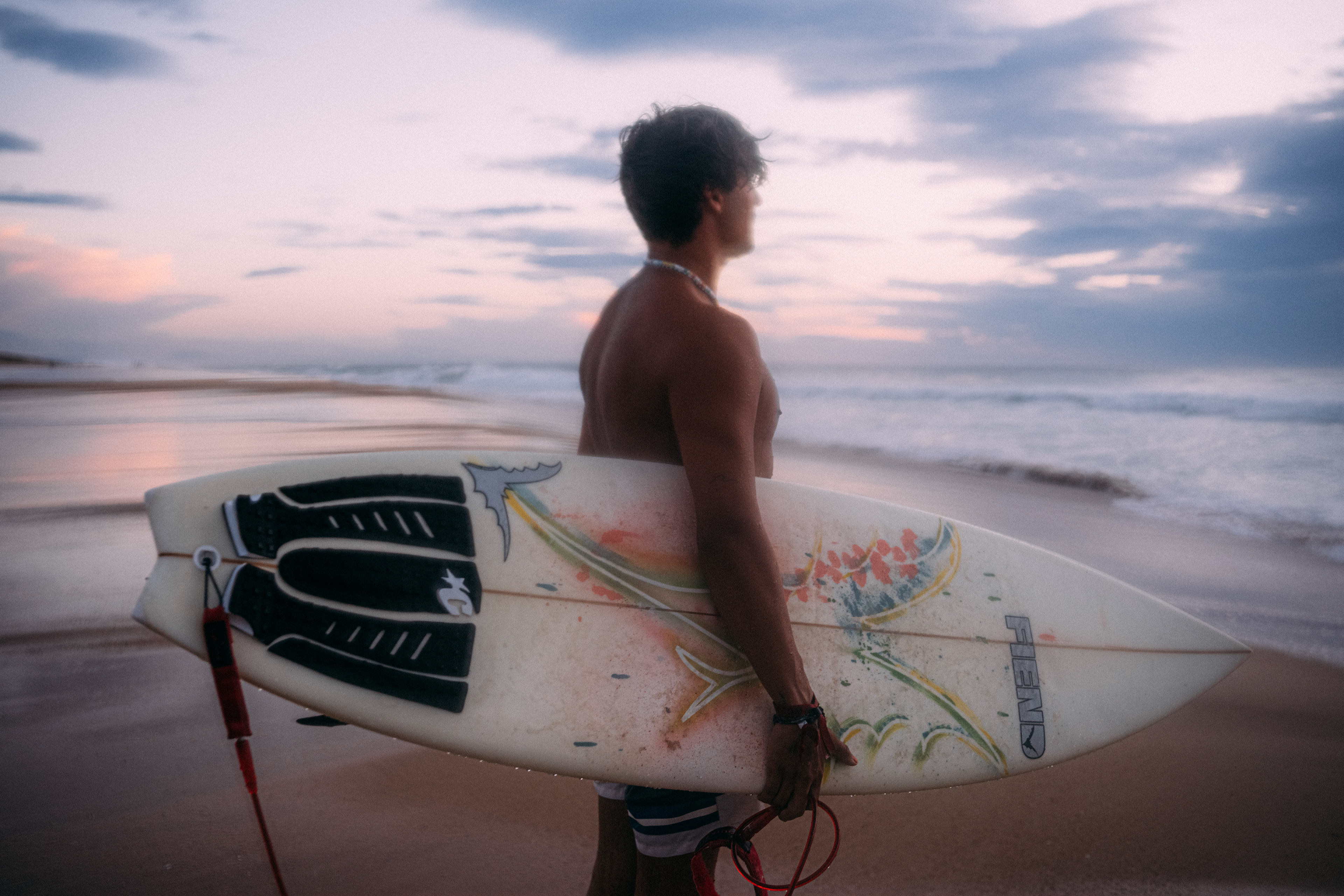Surfer paddelt hinaus ins Meer, um die perfekten Wellen der Blauen Stunde zu erwischen.