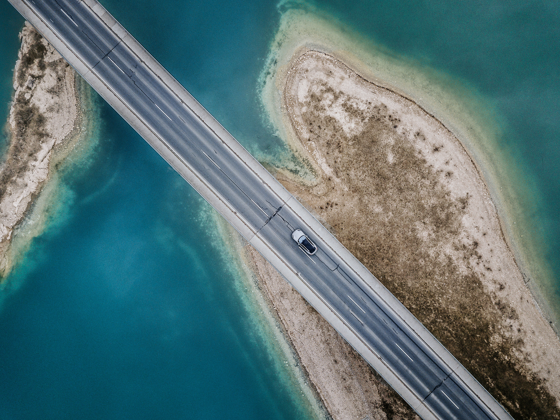 Drohnenbild eines Porsche Panamera beim Überholen eines Fahrradfahrers – Geschwindigkeit aus der Vogelperspektive.