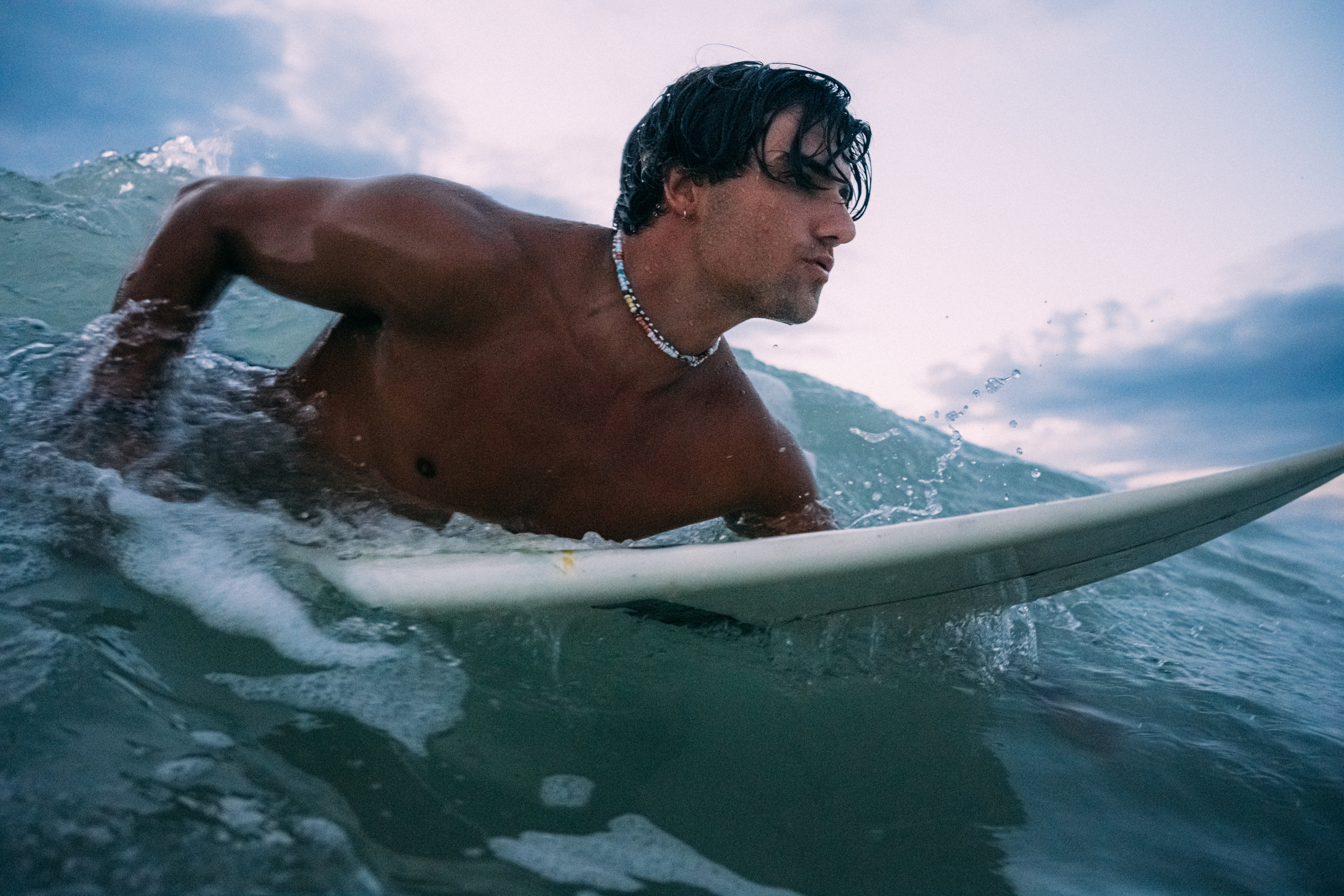 Stimmungsvolle Surf-Szene: Ein Surfer gleitet über das Wasser, während der Himmel in tiefem Blau leuchtet.