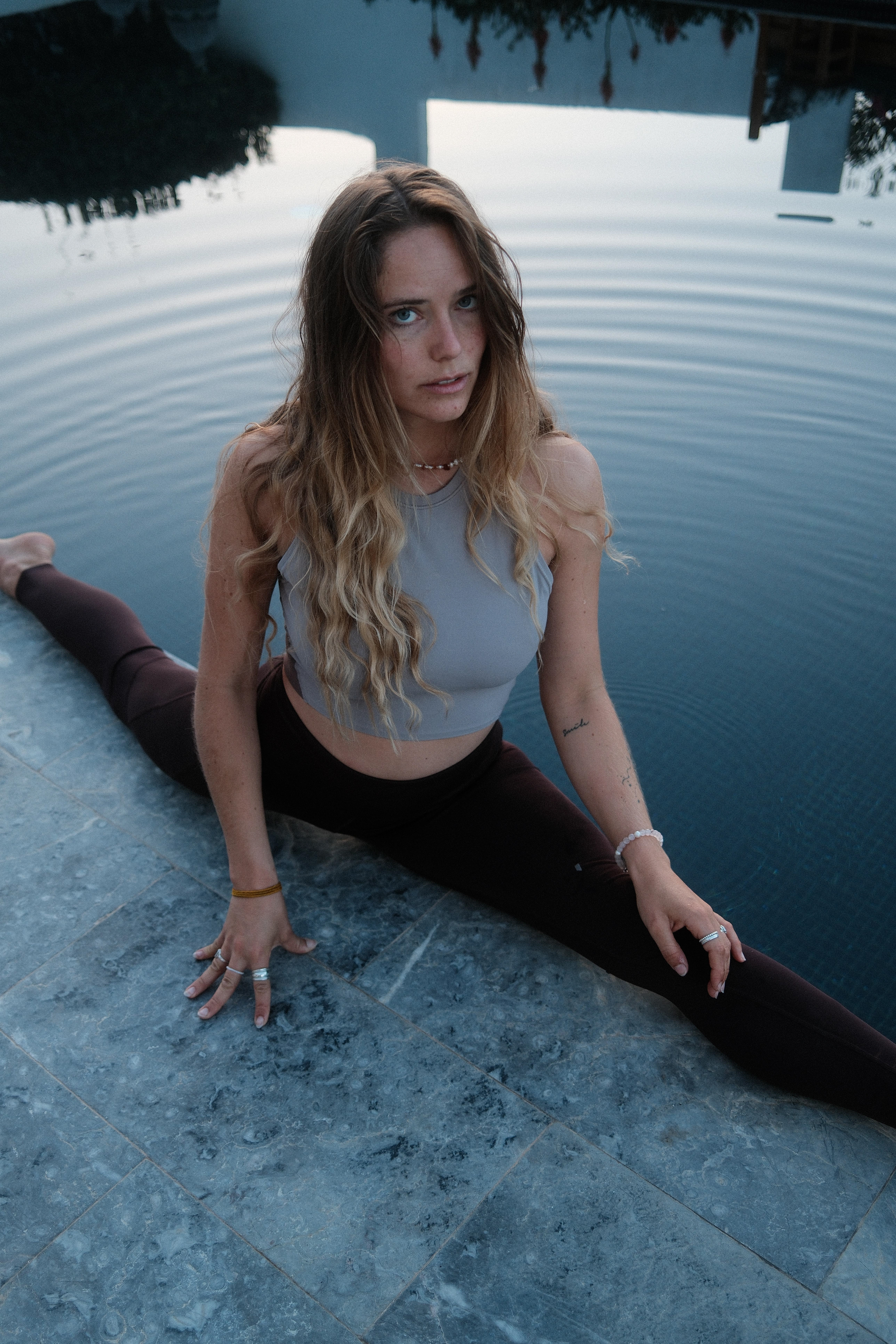 Person praktiziert Yoga am Pool, umgeben von warmem Sonnenlicht.