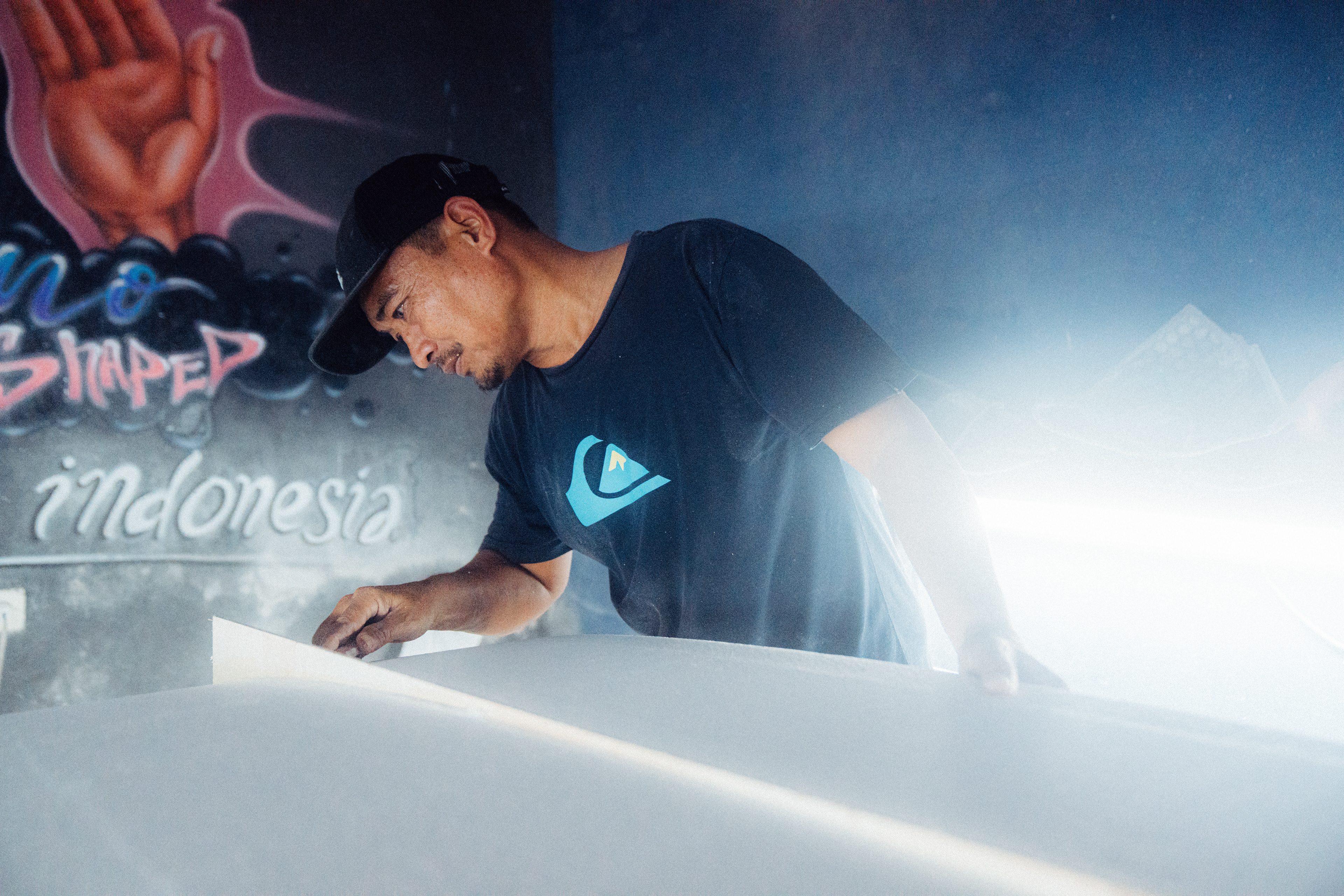 Ein erfahrener Shaper auf Bali prüft die Symmetrie eines frisch geformten Surfboards.
