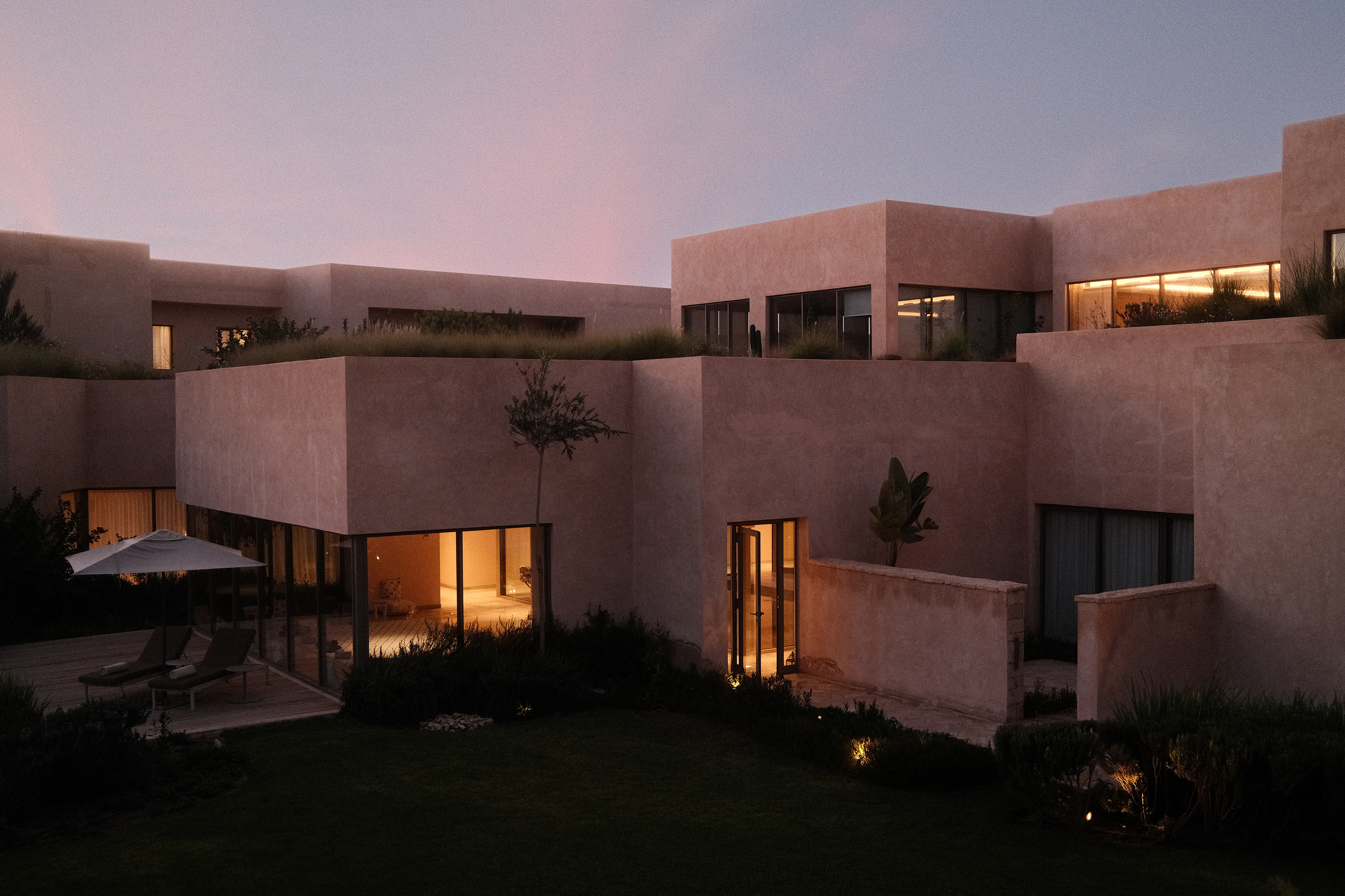 Moderne Hotelarchitektur bei Sonnenuntergang, stilvolle Außenansicht mit beleuchteten Fenstern.