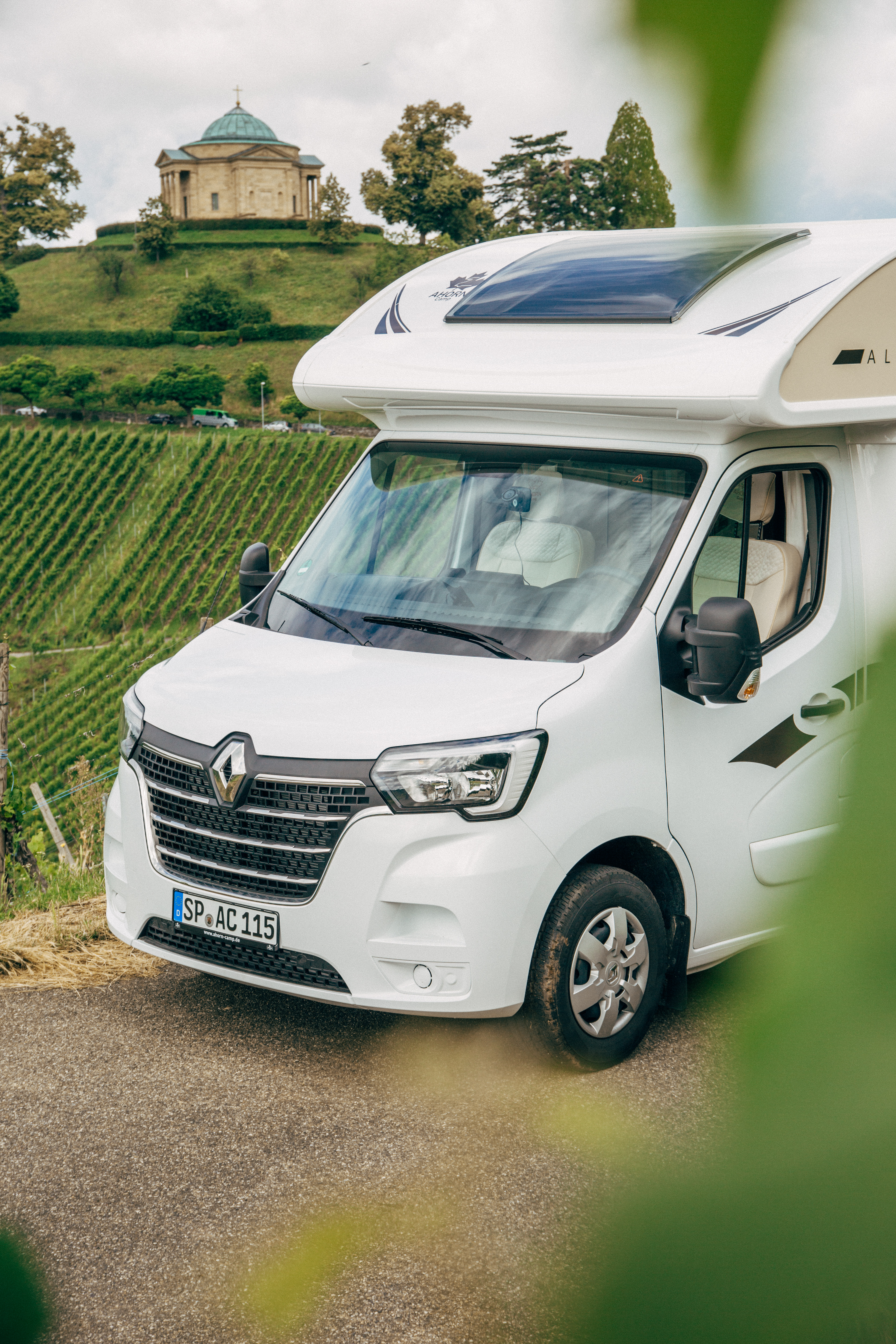 Ein Ahorn Camp Wohnmobil steht zwischen grünen Weinreben und lädt zum Verweilen ein.