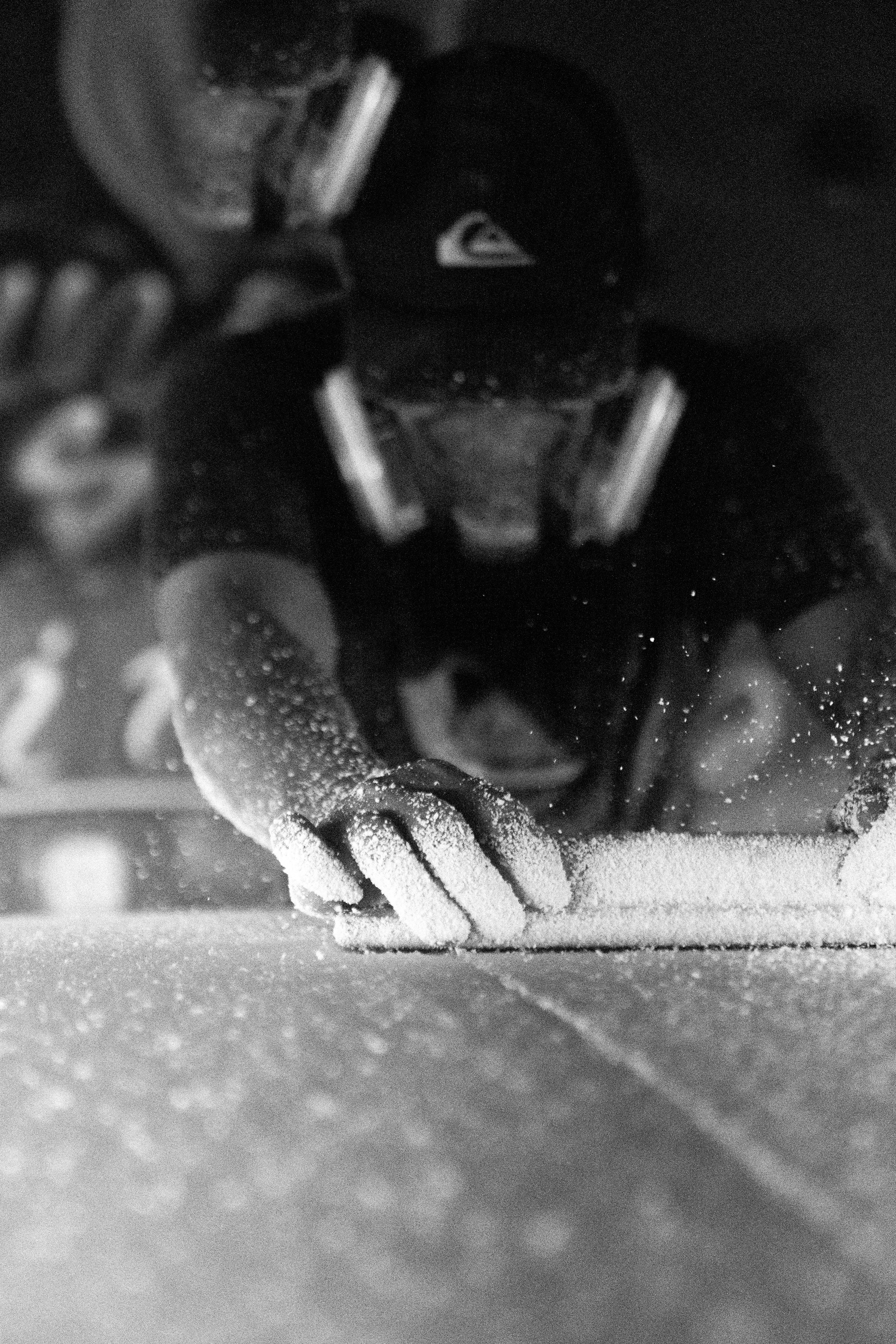 Ein erfahrener Handwerker benutzt einen Schleifblock, um das Surfboard in die gewünschte Form zu bringen.