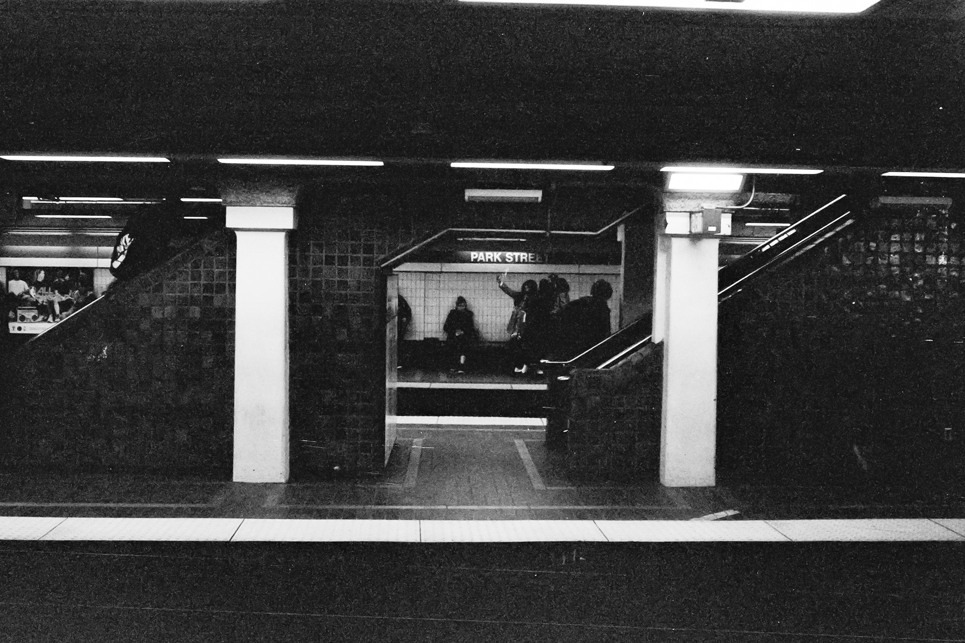 Black and white photo of two brilliant, white columns stand out in an otherwise murky, dark subway.