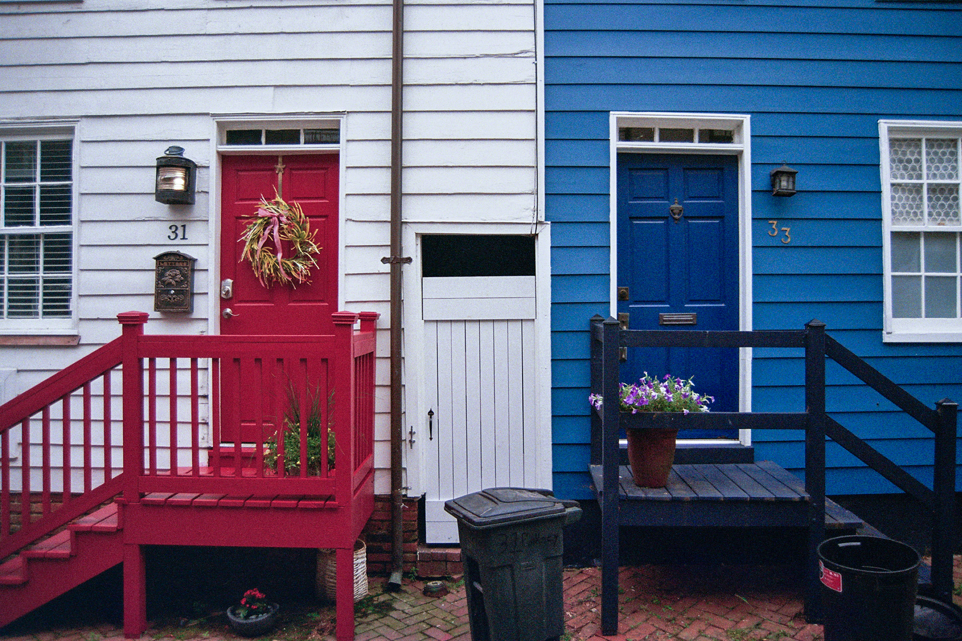 Houses painted red, white and blue stand symmetrically next to each other.