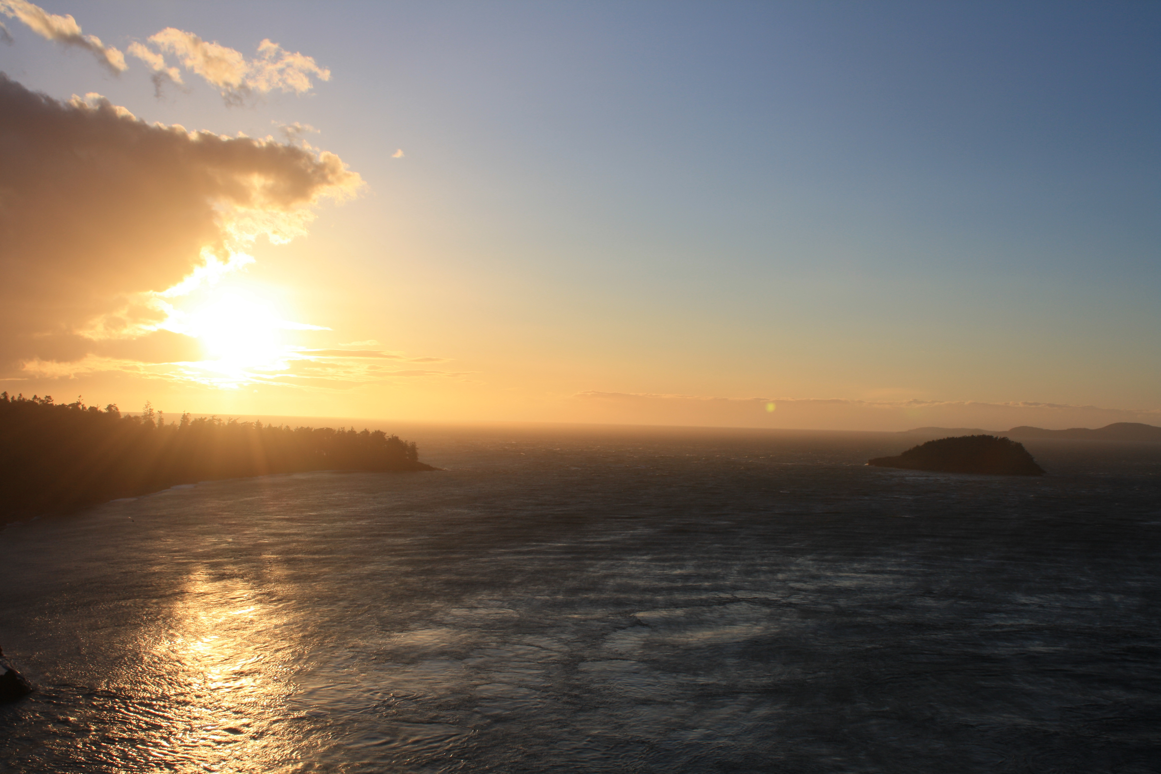 A sunset over a sweeping landscape of water and trees.