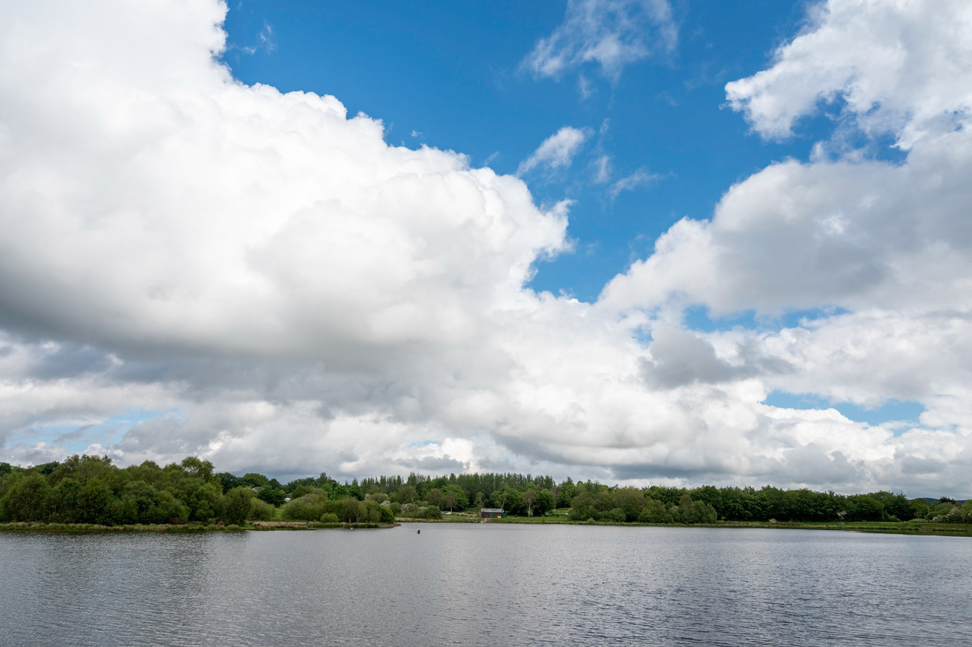 Clouds and blue sky over Pen Y Fan Pond near Blackwood, South Wales, UK