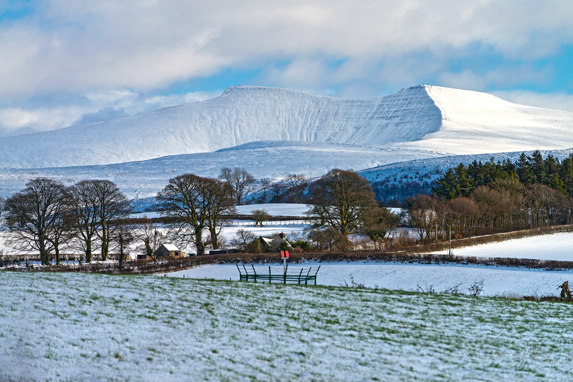 Late afternoon sun catches a snow covered Penyfan in The Brecon Beacons, South Wales