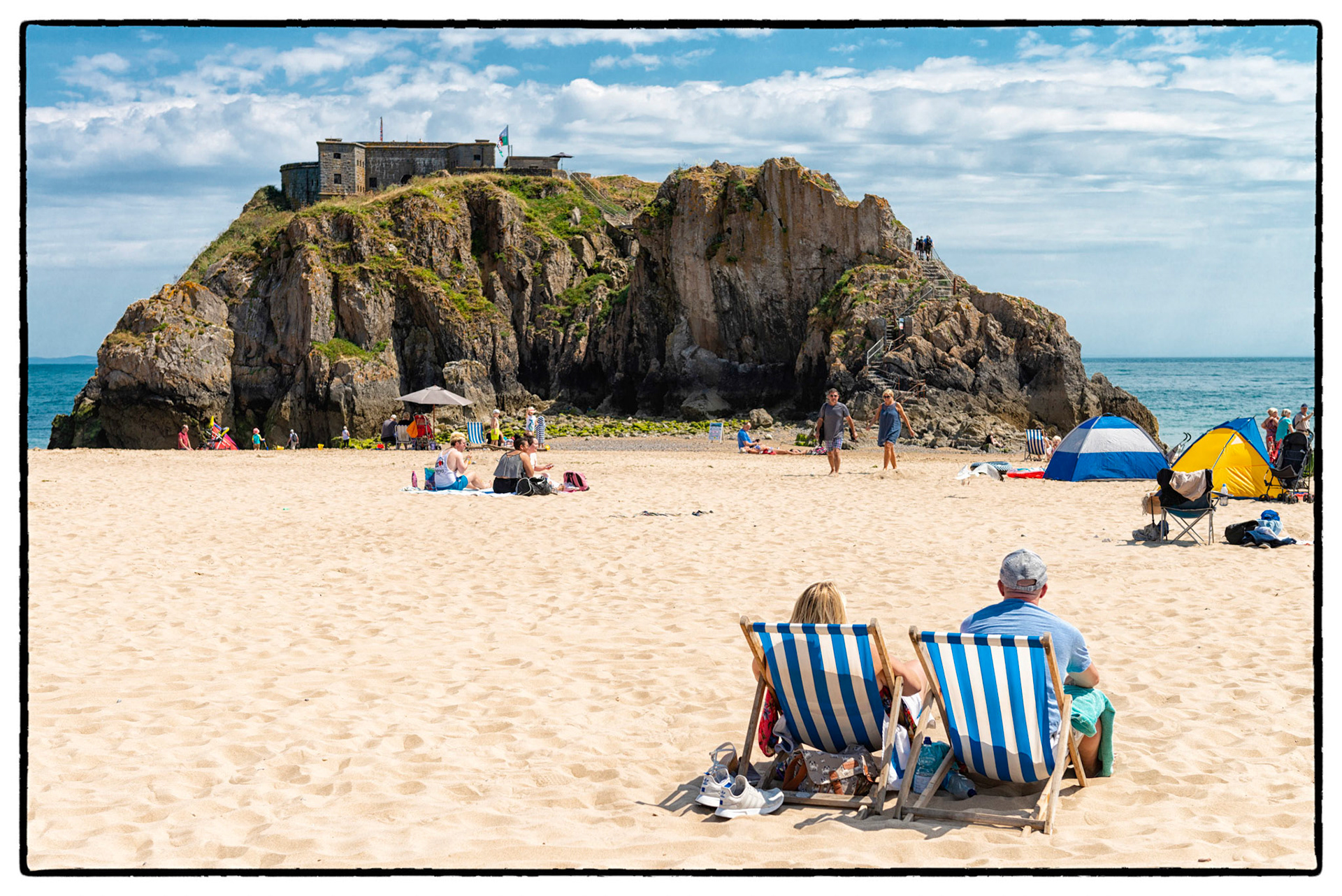 Holiday makers soak up the summer sun on Castle Beach in the pretty seaside town of Tenby, Pembrokeshire, Wales, UK