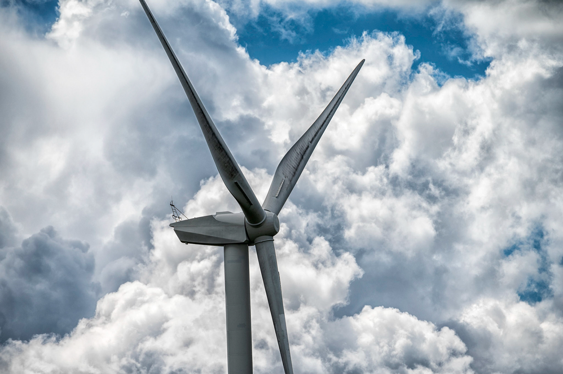 Wind turbine at Penyfan Pond, near Blackwood, South Wales against a dramatic cloudy blue sky.