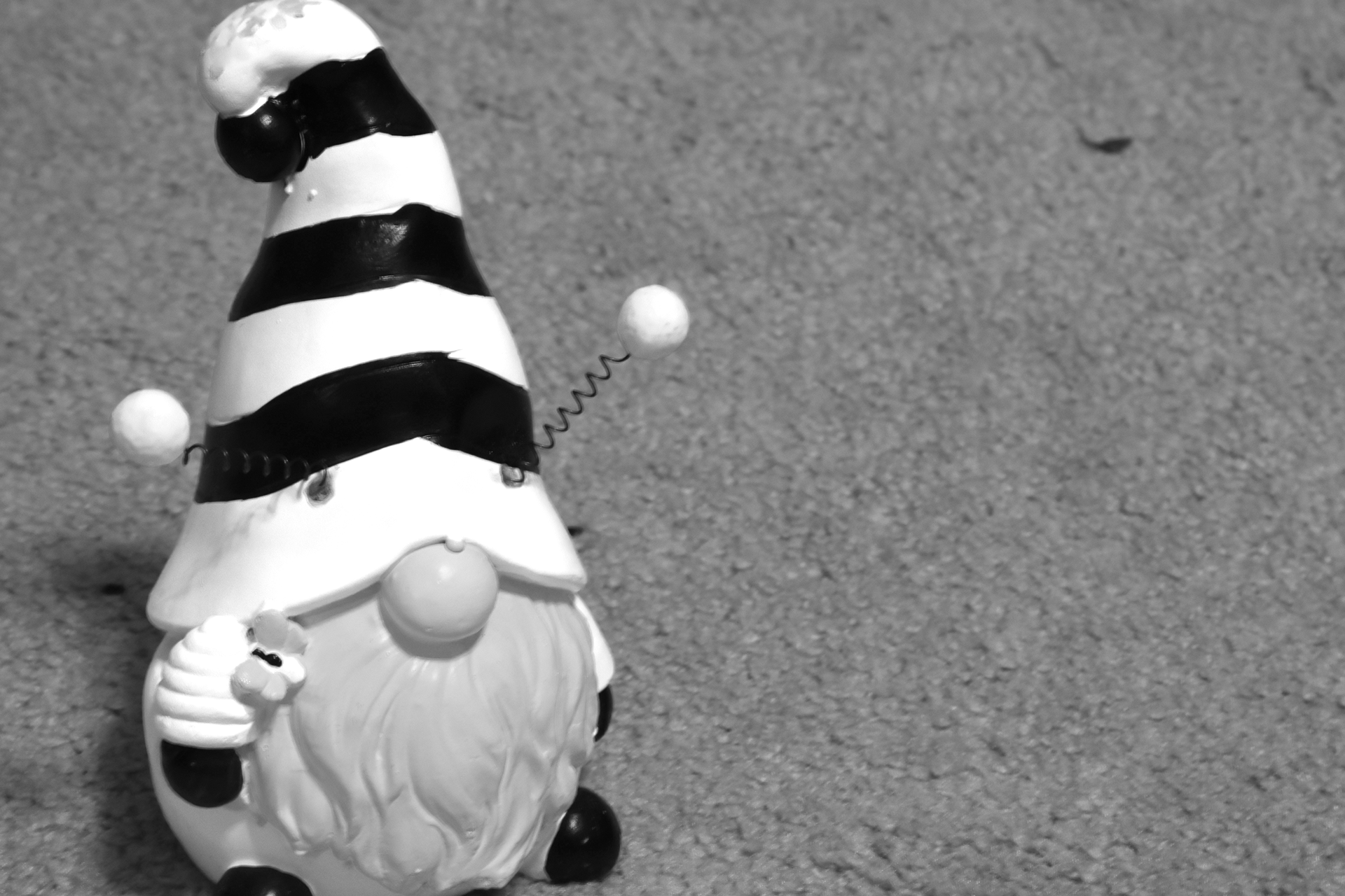 A black and white shot of a gnome in a bee outfit