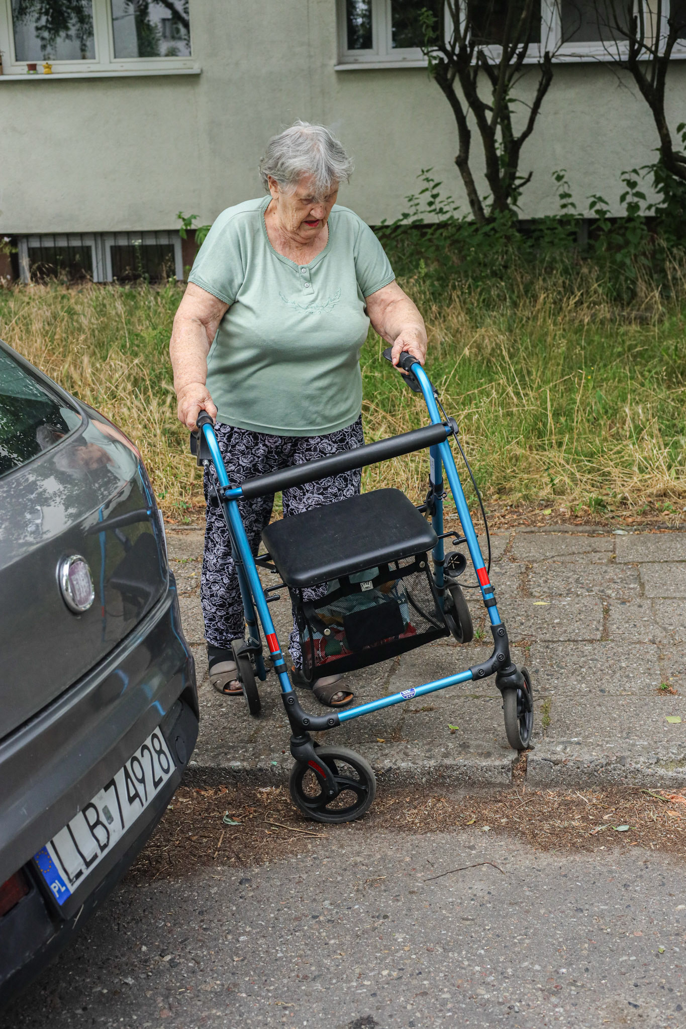 80 Year old Ms Teresa walks trying to cross the kerb but the wheel has locked and she has no power to move (6/2023)