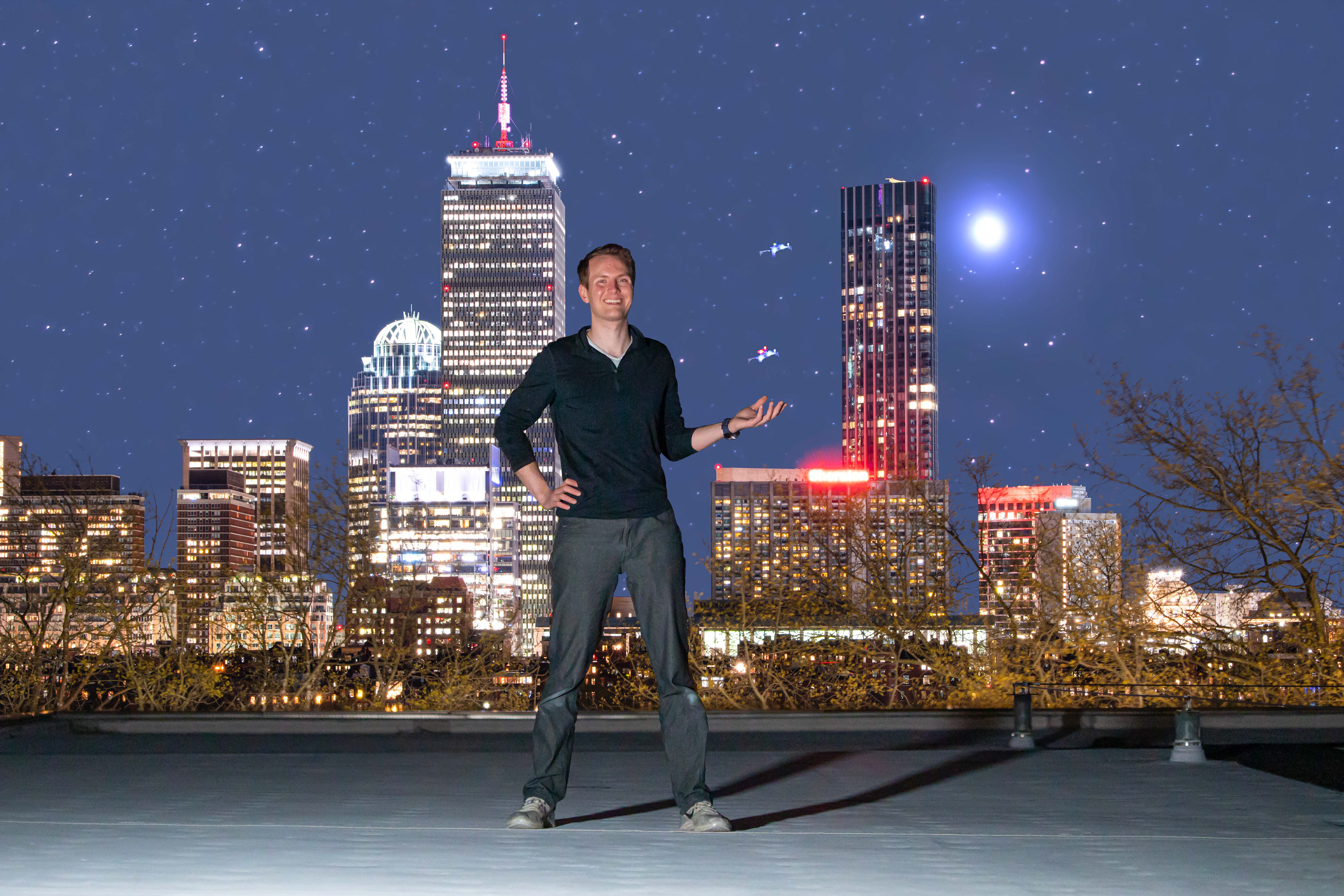 Composite of six different images: One photograph of Charles, one to artificially light the foreground, one to capture each drone suspended in the air with wire, one of the Boston skyline, and one of the starscape. A fog filter was used to intentionally add a diffuse appearance to the starscape and a long focal length lens was used to achieve the desired tightly - framed foreground - background perspective. Cambridge, MA.