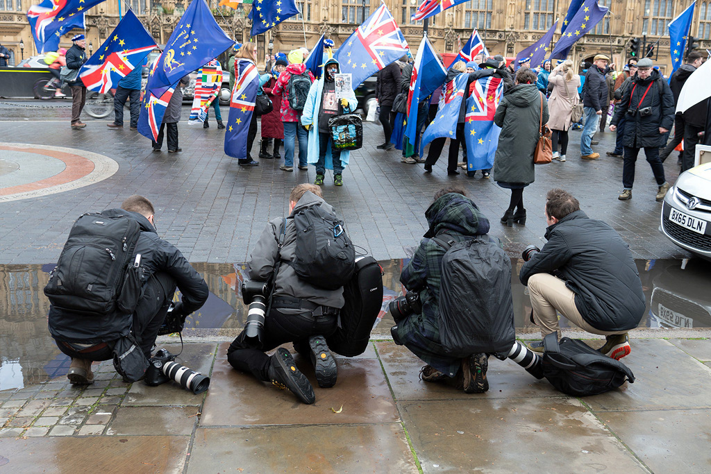 Photographers outside Parliament take advantage of a puddle