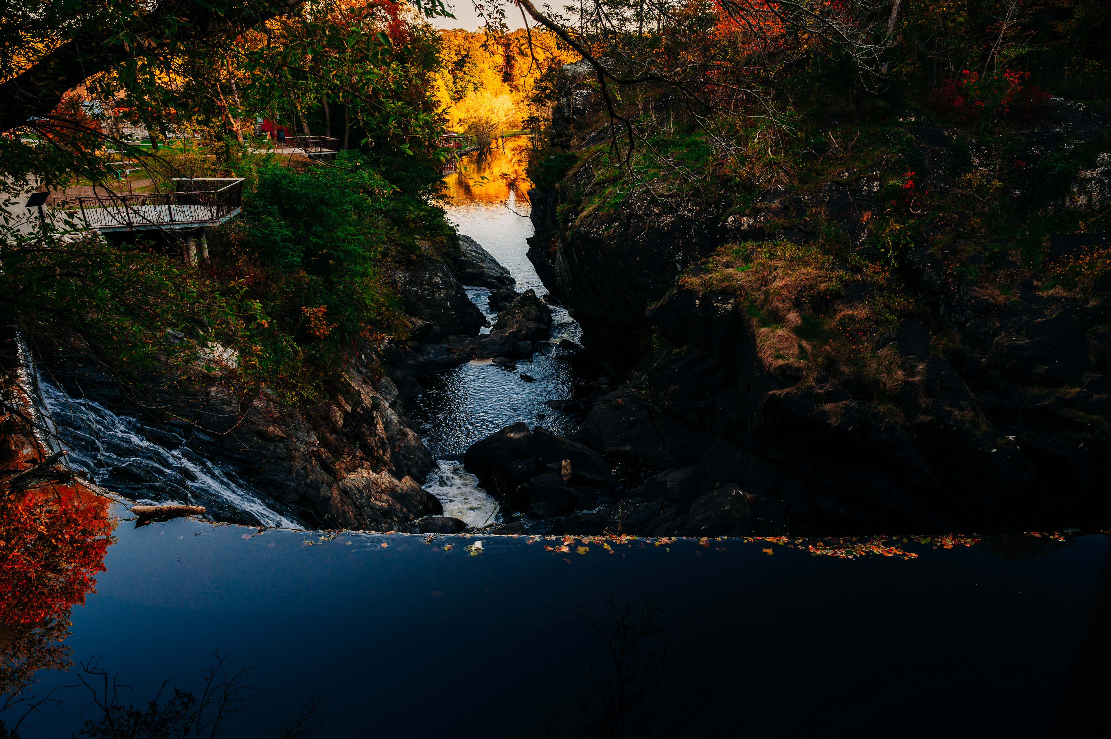   A scenic view of a river with rocks and colorful autumn leaves, surrounded by trees. 