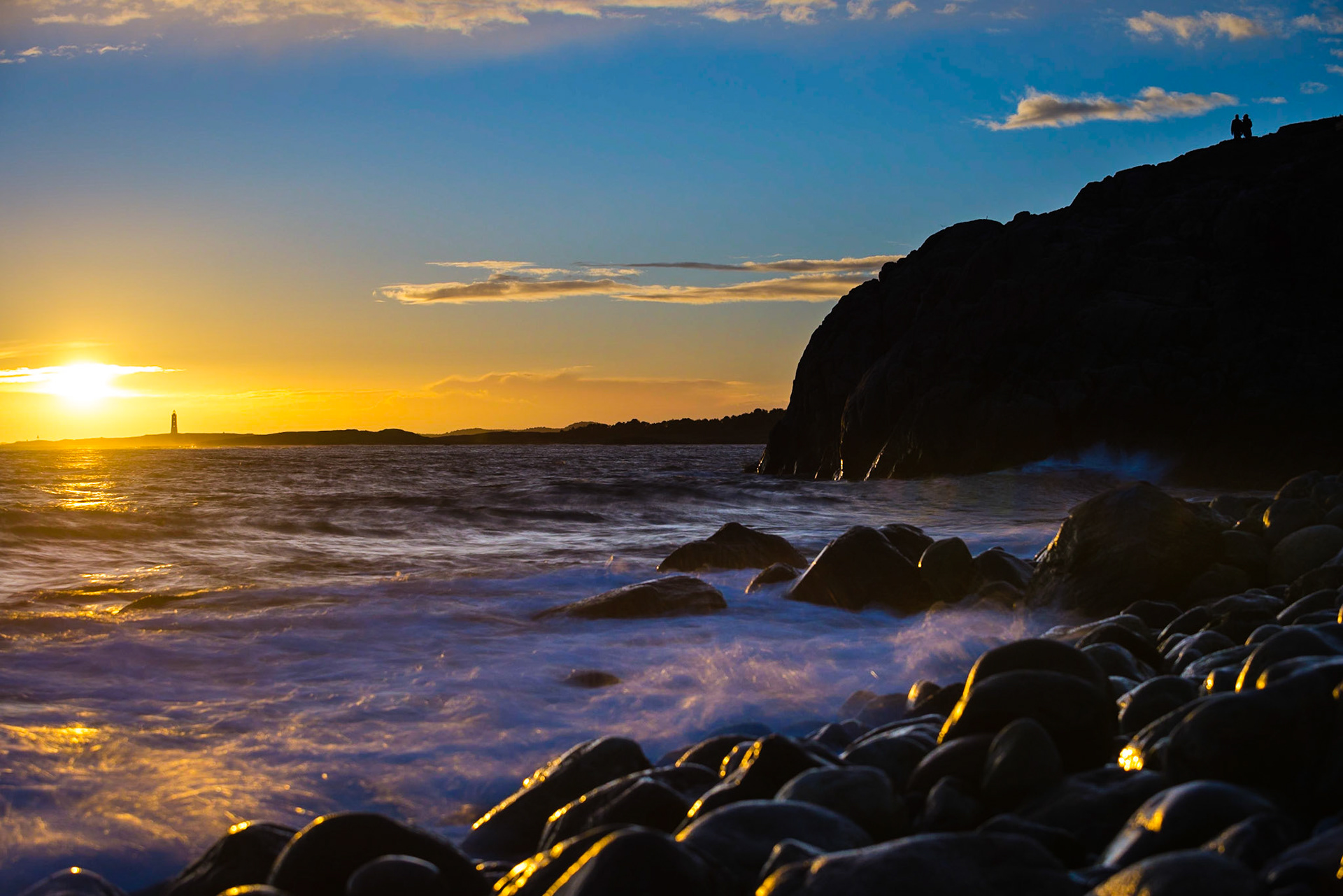A couple watching the sunset at Tromøya, Arendal, Norway.
