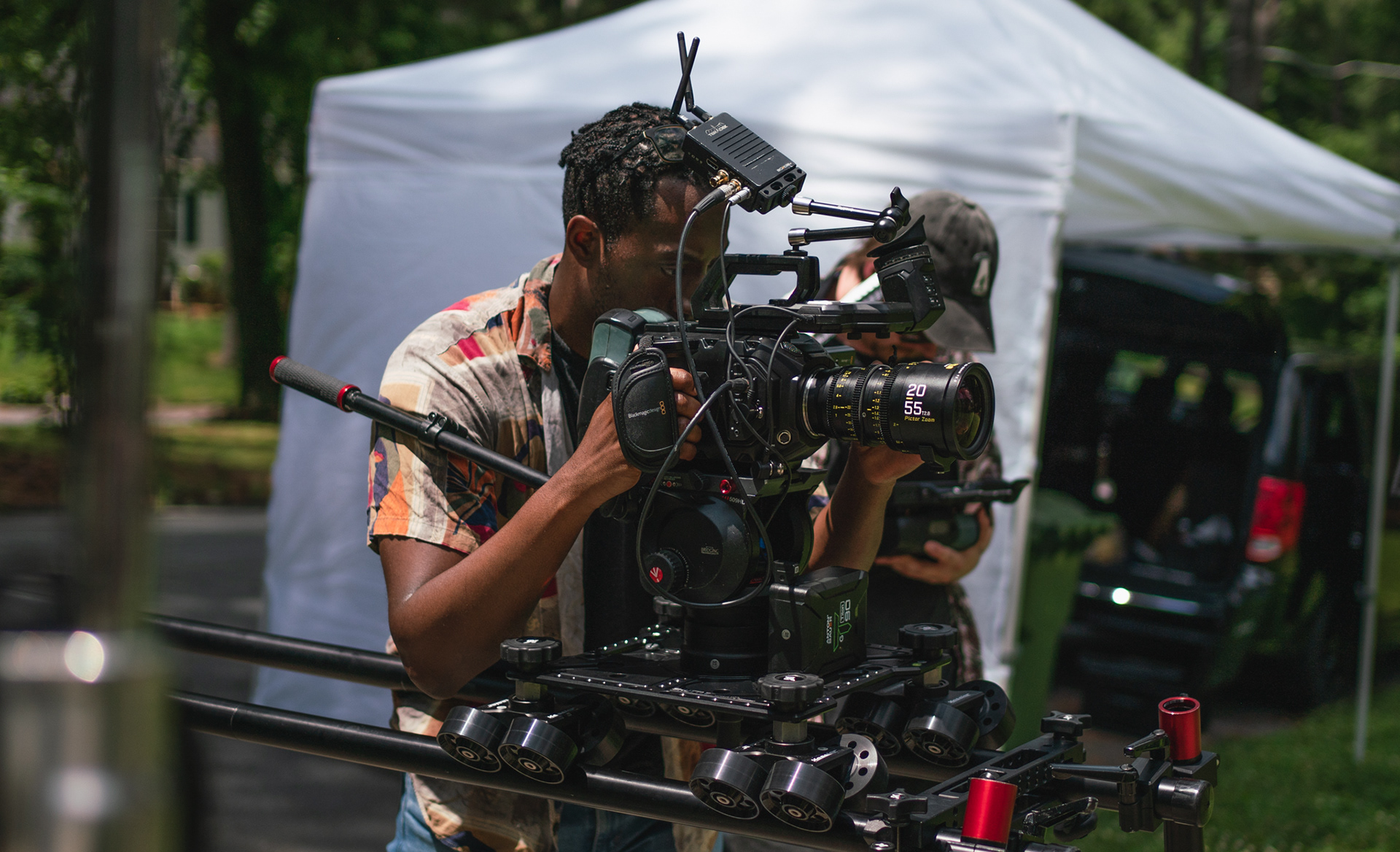 Kimani Oletu looking into the viewfinder of a camera.
