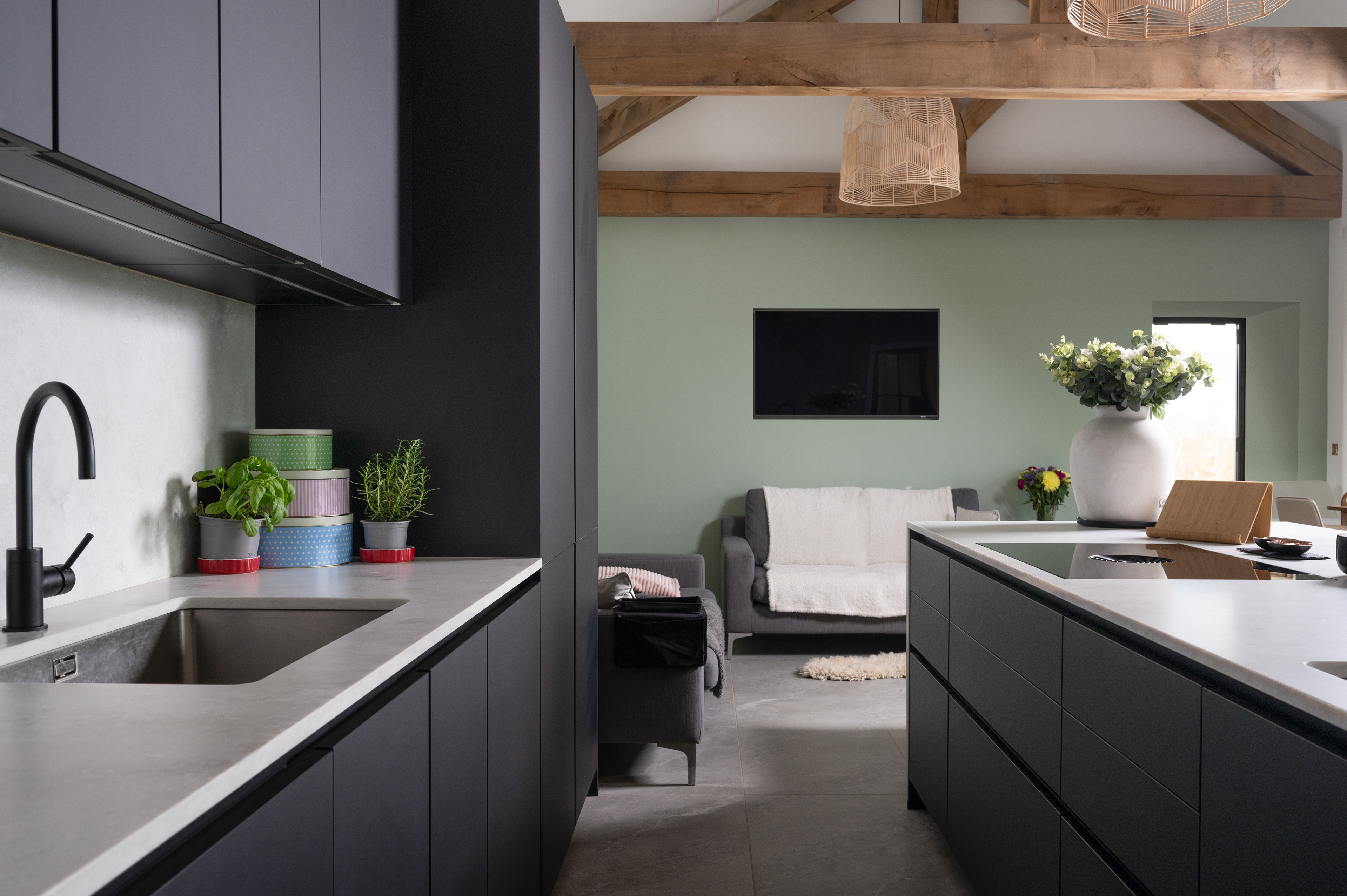 A photograph of a kitchen with modern, handle less cupboards in charcoal grey. 