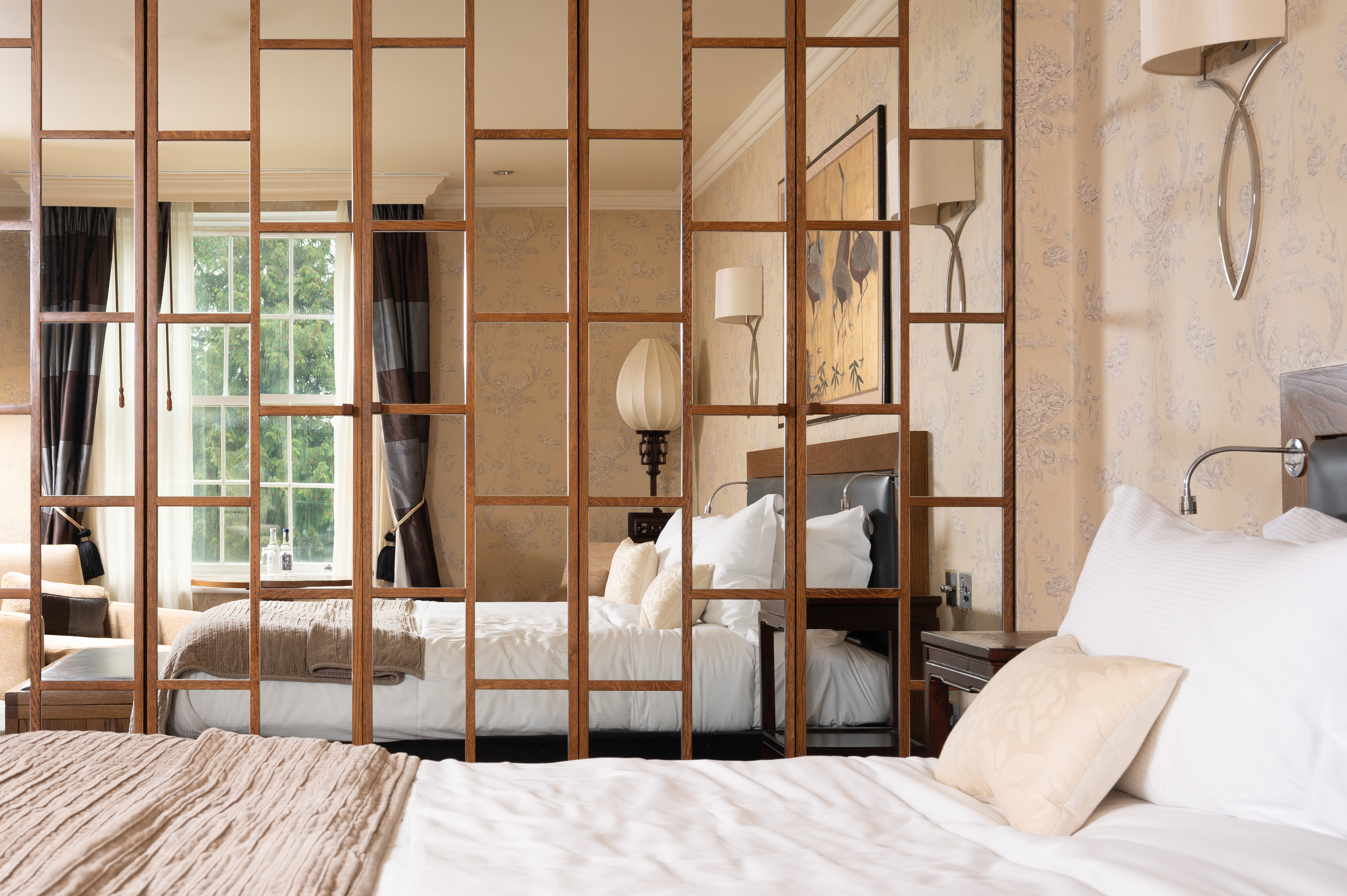 A photograph of a hotel bedroom with panelled mirrored doors