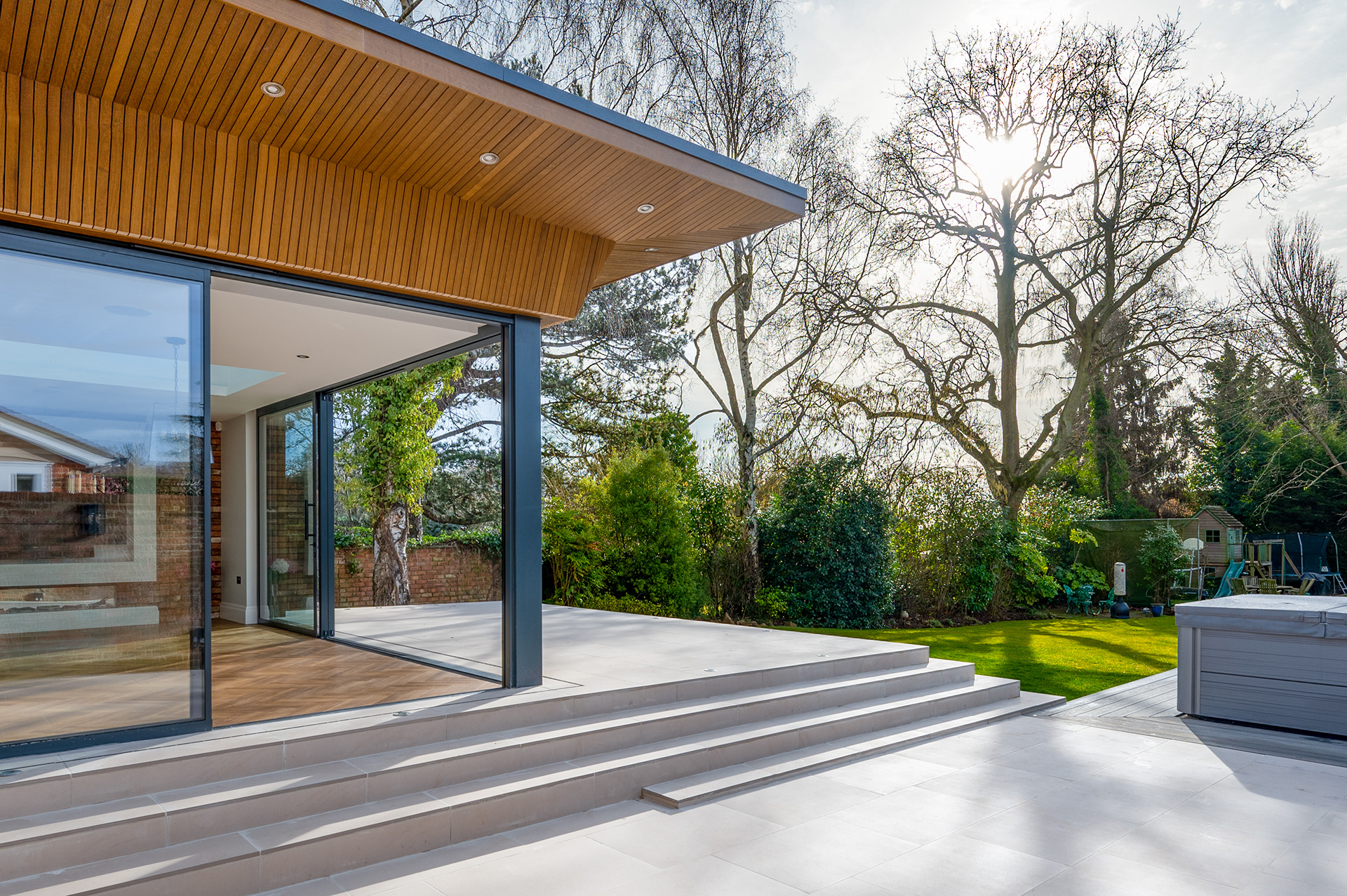 Photograph of the rear corner of a house. The house has large sliding doors that meet at the corner.