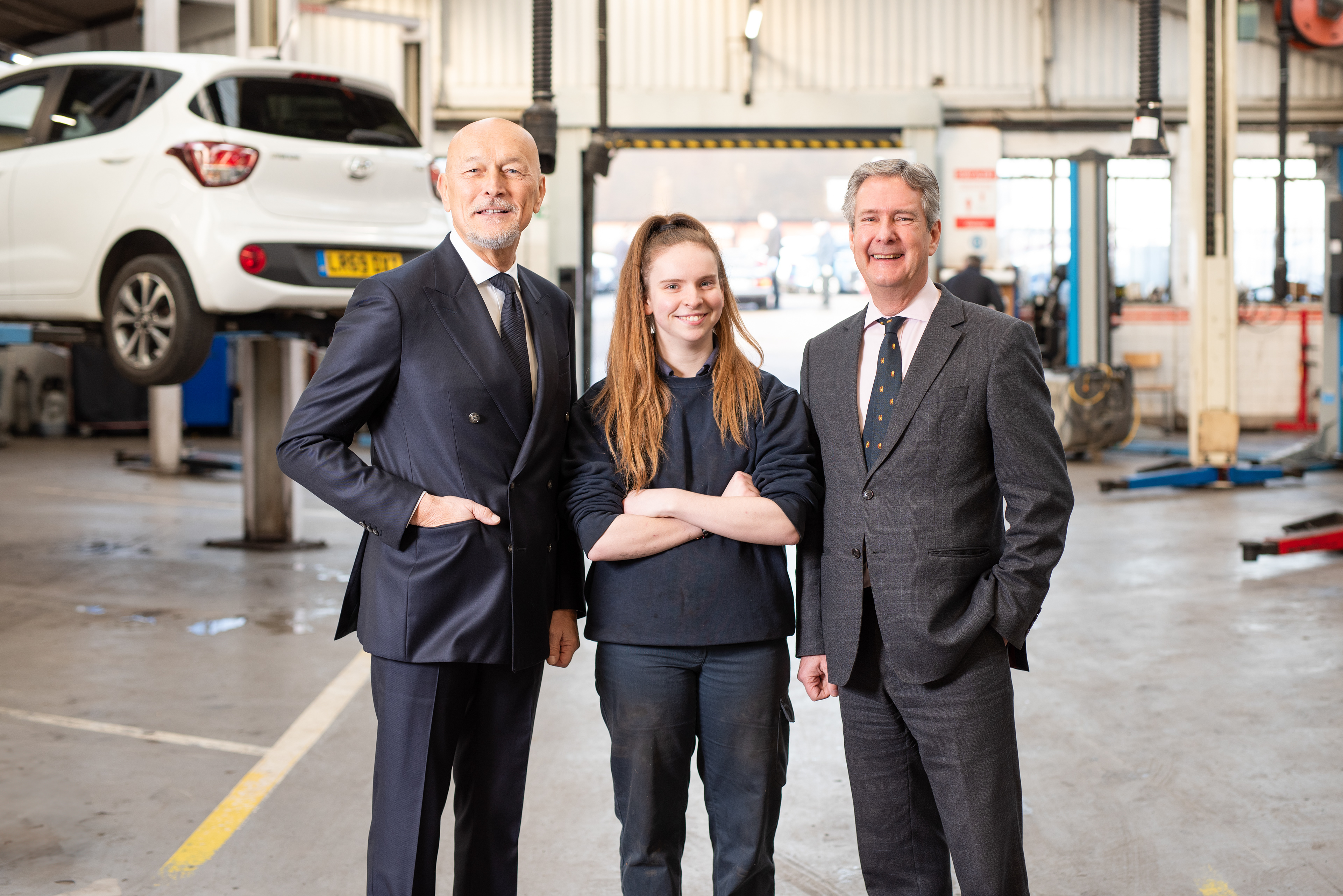 A portrait of three people in the inside of a mechanics workshop