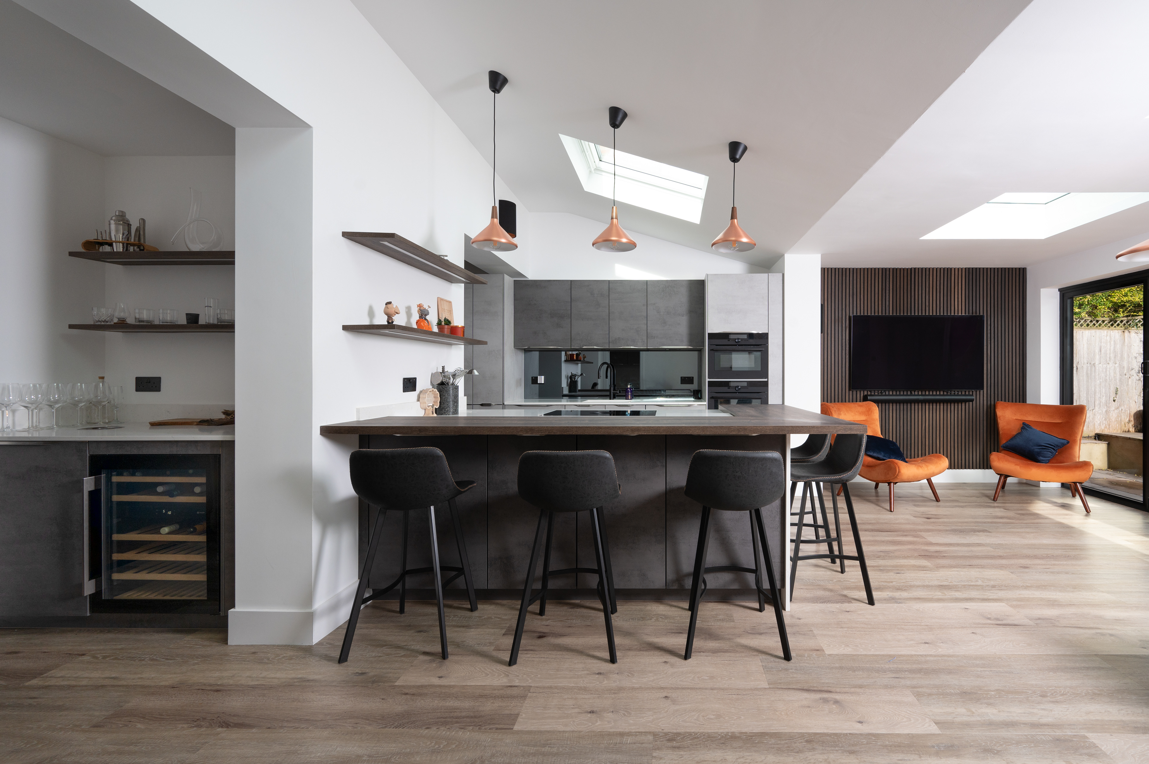 A photograph of a modern kitchen with a bar area and wine fridge.