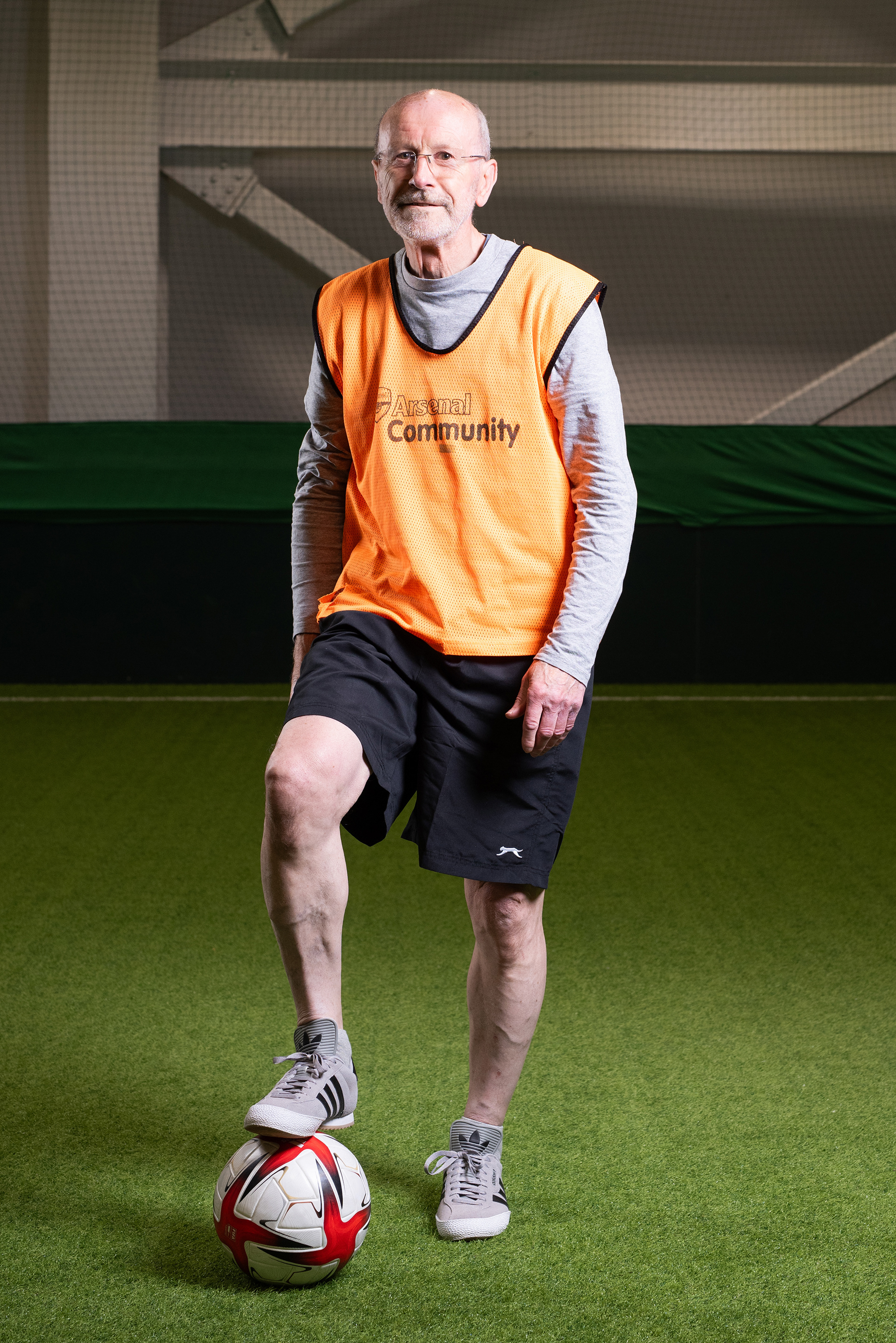 A photograph of a man in sports clothes with his foot on a football