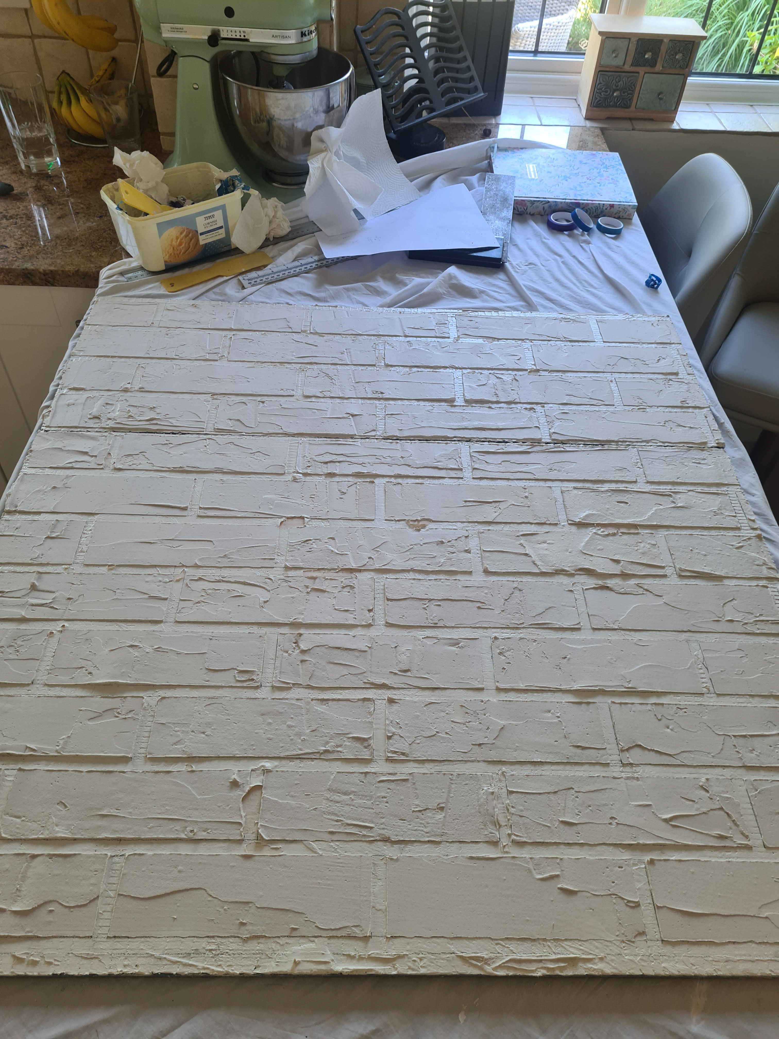 Building up filler to create a 3D brick texture and then removing the masking tape