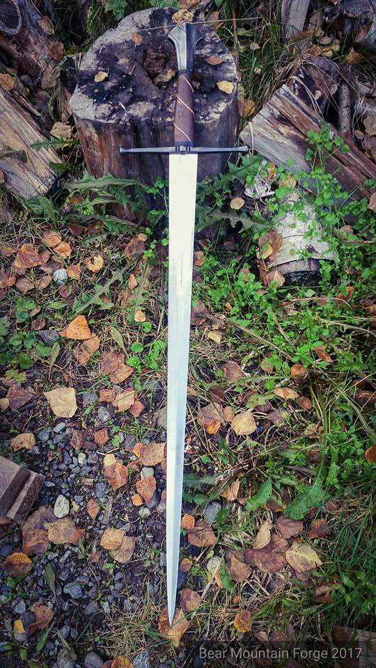 46 inch long sword with 35.25" blade. Pommel is hollow ground and filed. Fittings are mild steel heat blued than chemical blue topper that I brushed back to a dull grey with the heat blue shimmering through. Handle is Wenge wood, with inlaid twisted copper wire, bordered with tooled and dyed leather sealed with boiled linseed oil. Peen block is brass. Blade is 6150. Weight is 3lbs 12 ounces with a POB of 3.5 inches.