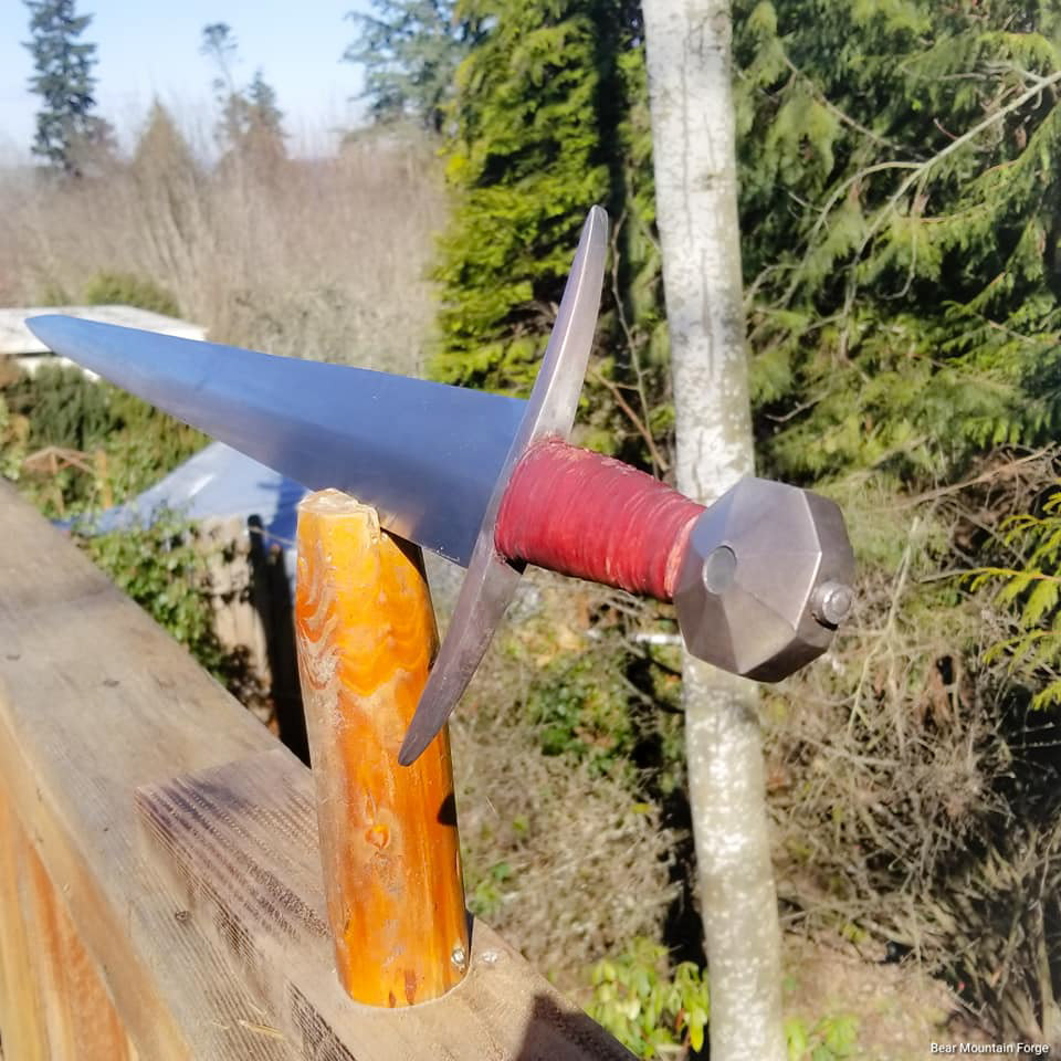 Type XVIII arming sword. 5160 blade, mild steel guard and pommel with a copper patina. Handle is poplar with cord and dyed leather. Pommel is keyed and peened, guard was hot fitted and peened. Final blade polish then off to Australia. OAL: 34.25" Blade: 28" PoB: 3.5" Weight 2.6 lbs