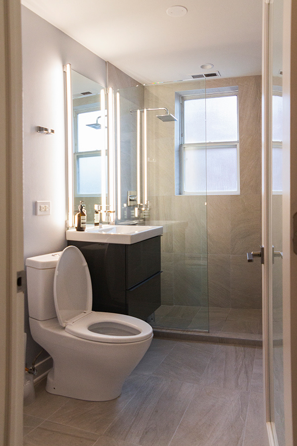 Bathroom design for the fernandes residence in chicago features large tile, glass enclosed shower and a floating vanity