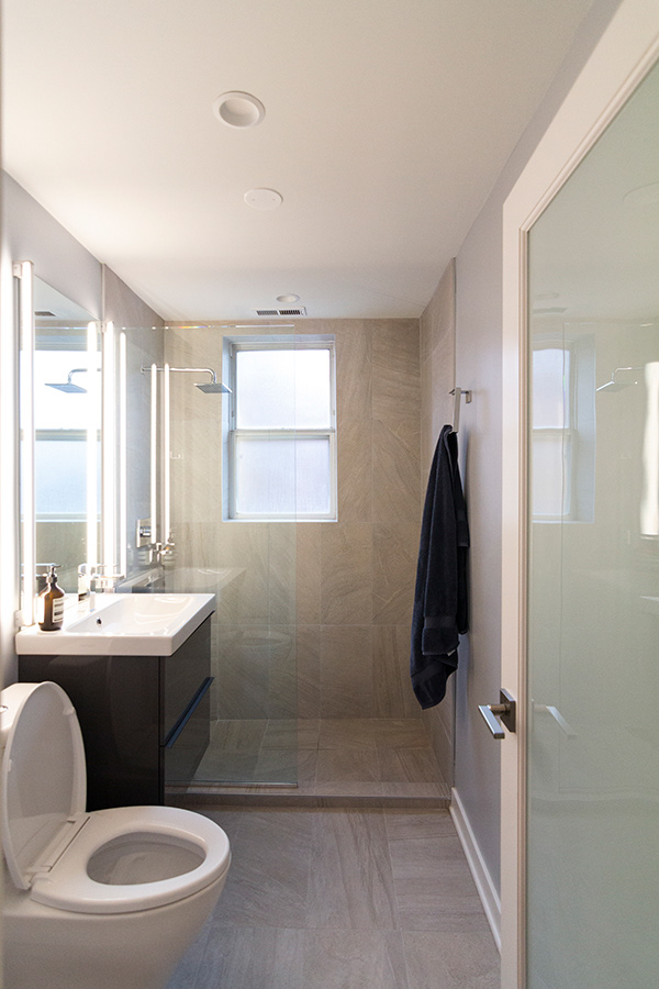Bathroom design for the fernandes residence in chicago features large tile, glass enclosed shower and a floating vanity