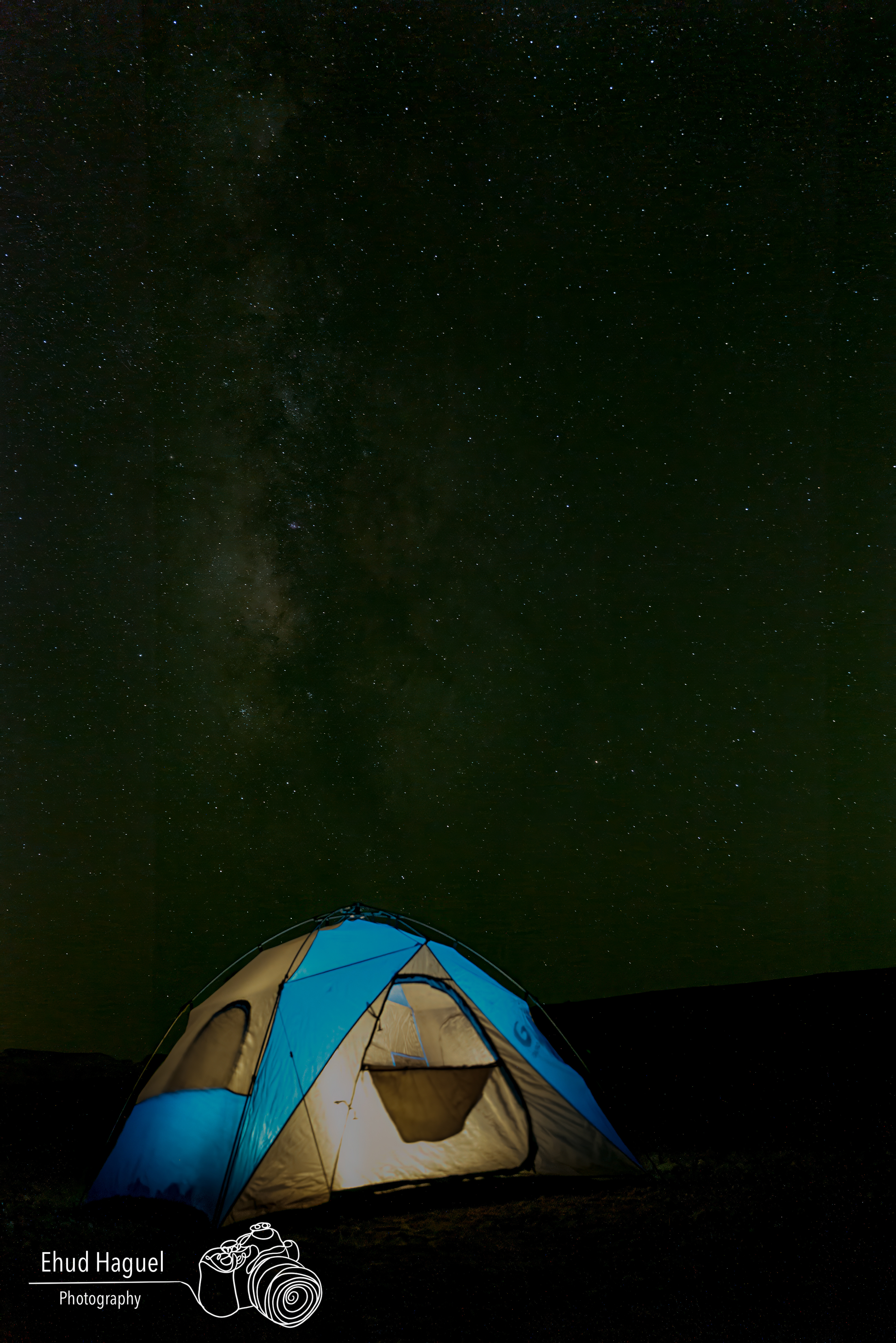 Milky Way over illuminated tent, night sky photography Israel