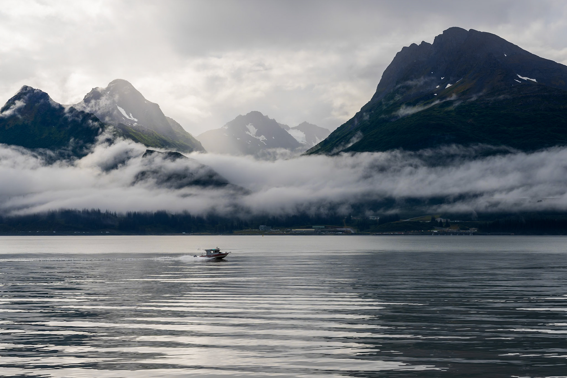 A lone boat travels across the Port of Valdez on a calm morning.