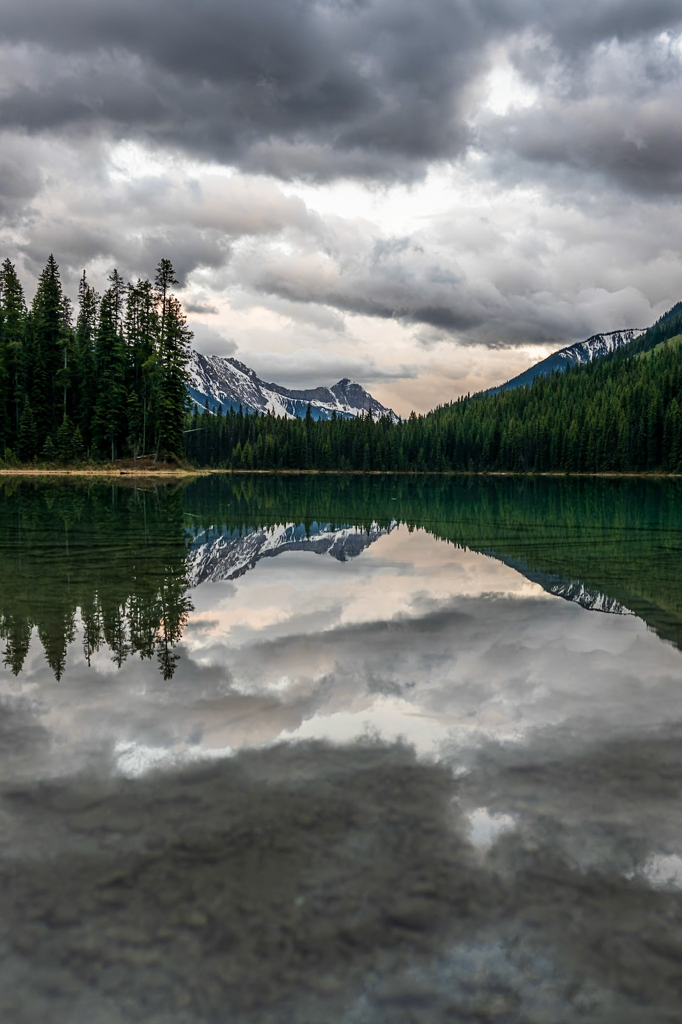 Monroe Lake in the Bull River Valley glows with warm evening light, its calm waters perfectly reflecting clouds above.