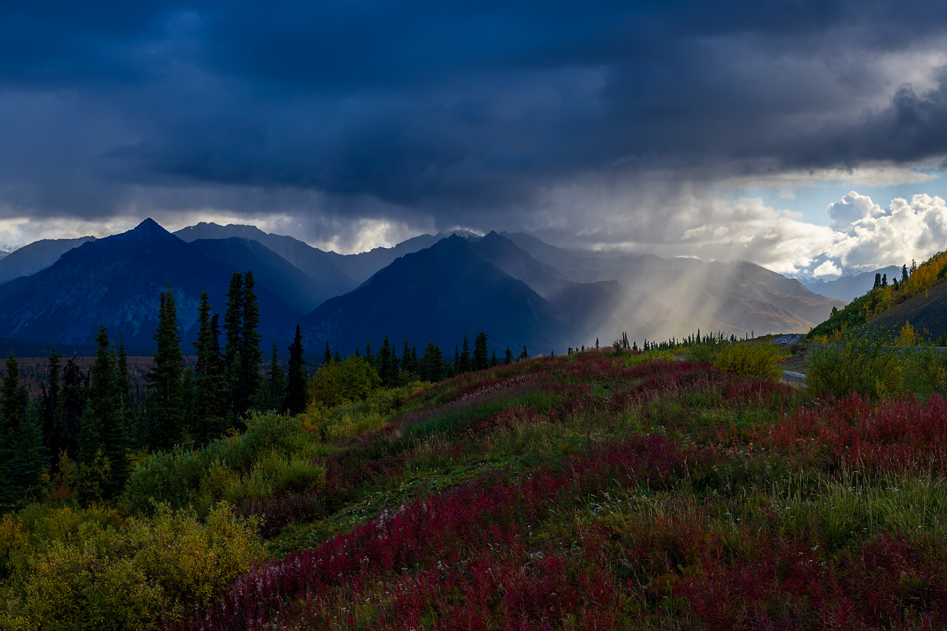 A dramatic view from the Glenn Highway across shadowed peaks and fall vegetation.