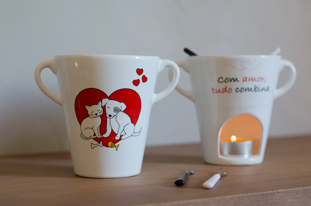 A porcelain fondue cup with an illustration of a cat and a dog in love. On the back of the cup, it says "With love, everything matches."
